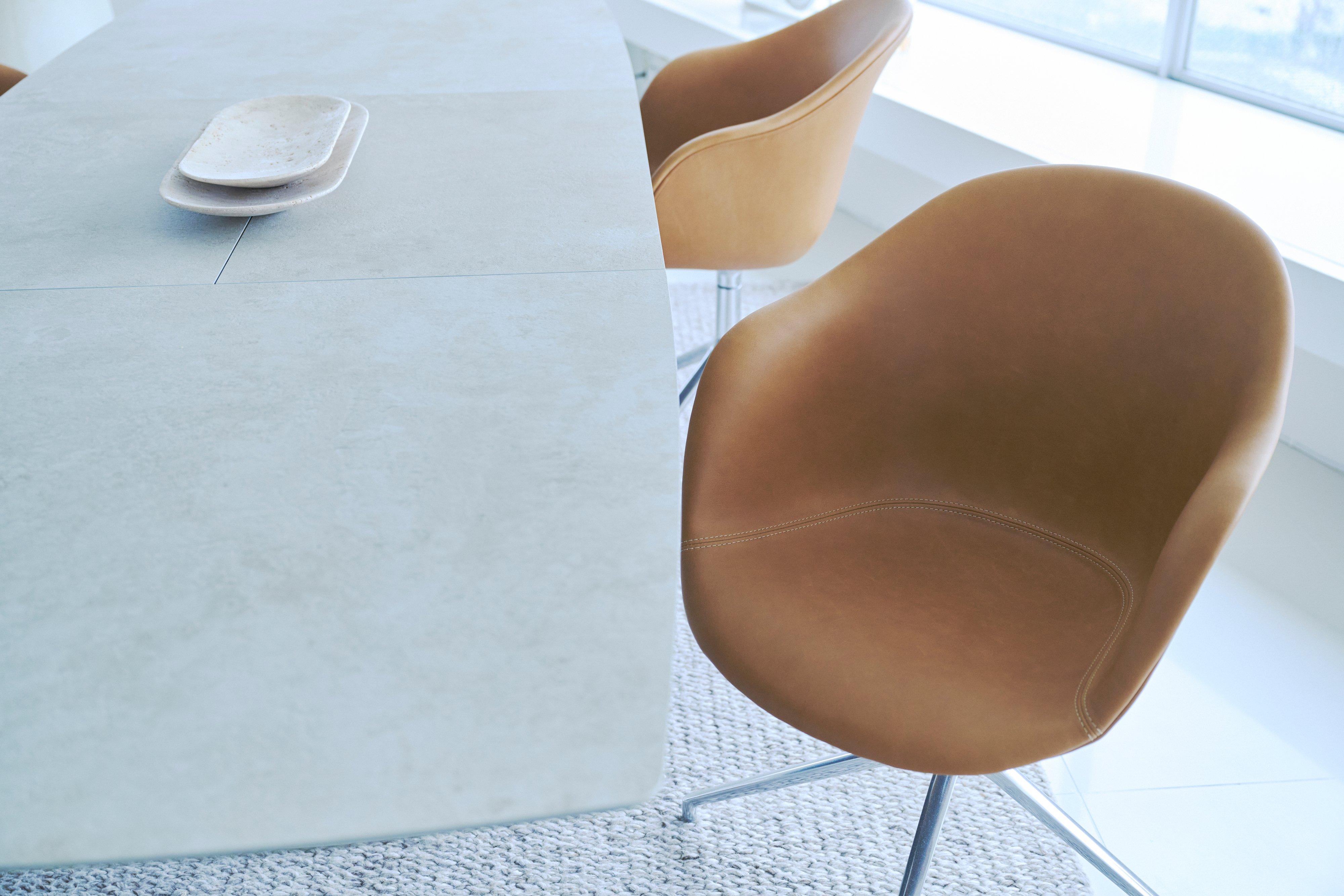 Tan upholstered dining chairs with metal legs beside a modern dining table.