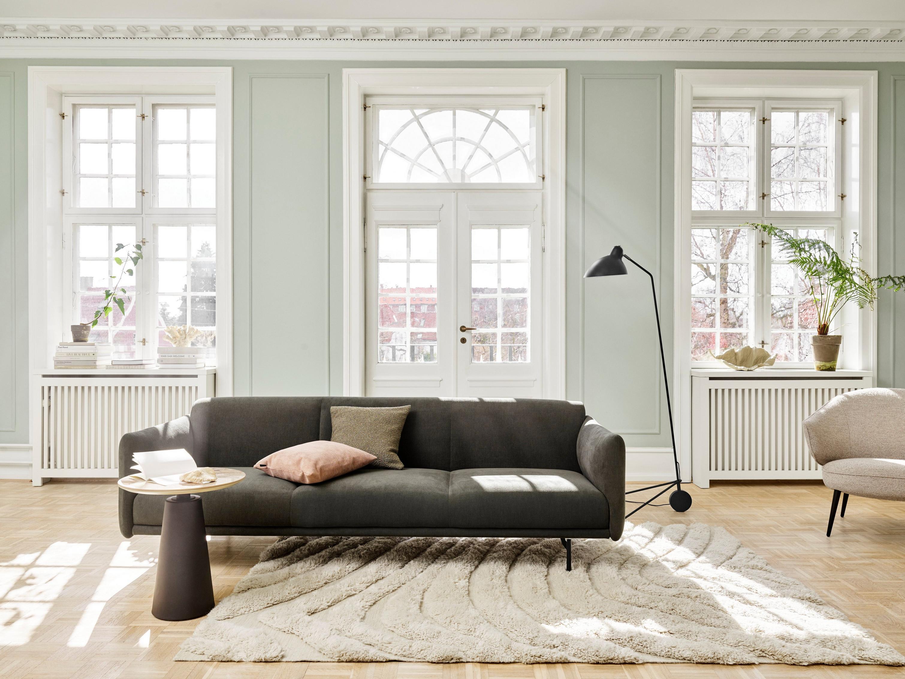 Sala de estar luminosa com o sofá Berne, a mesa lateral Madrid e o candeeiro de chão Demand.