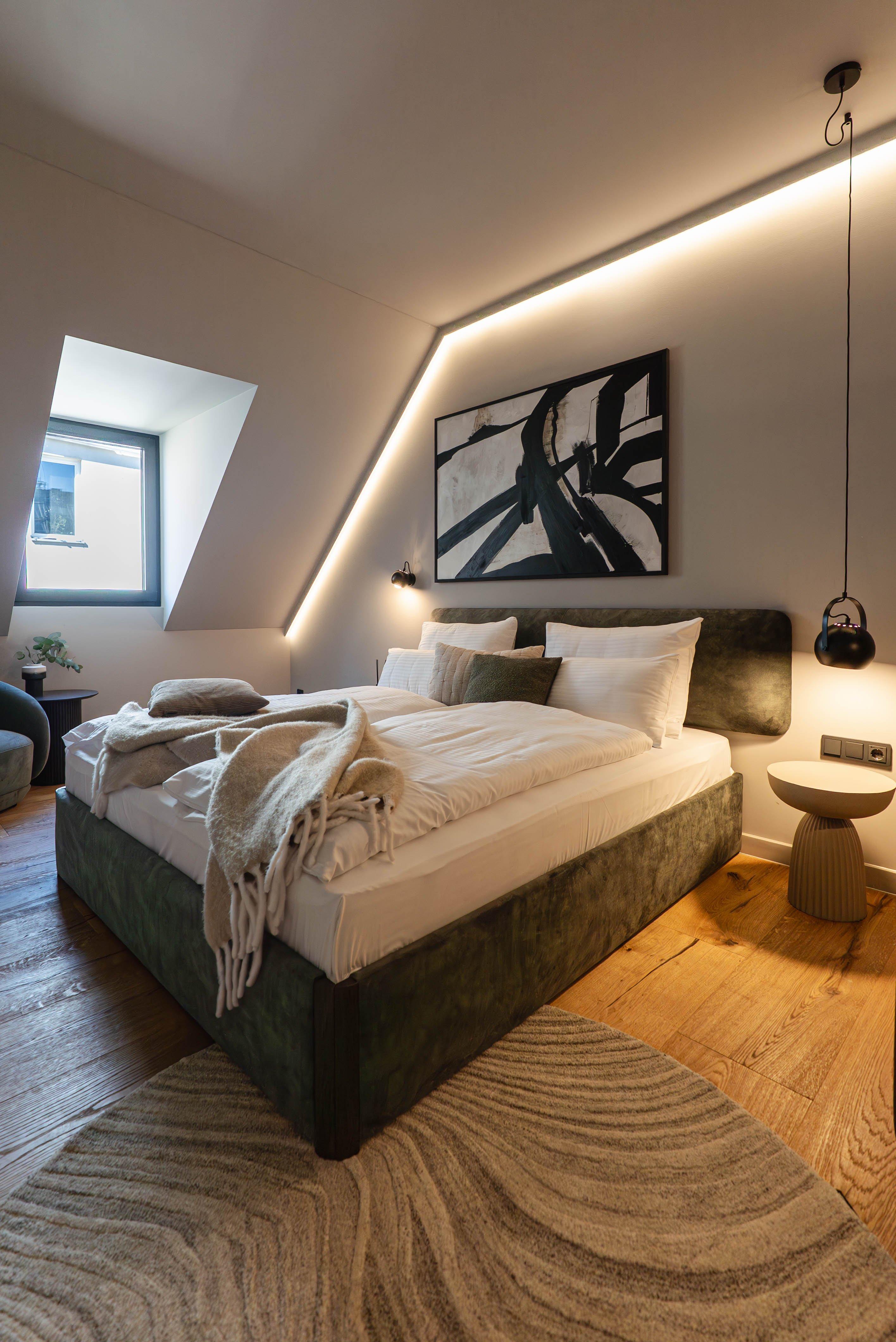 Chambre moderne avec lit double, tableau abstrait et lumière douce.