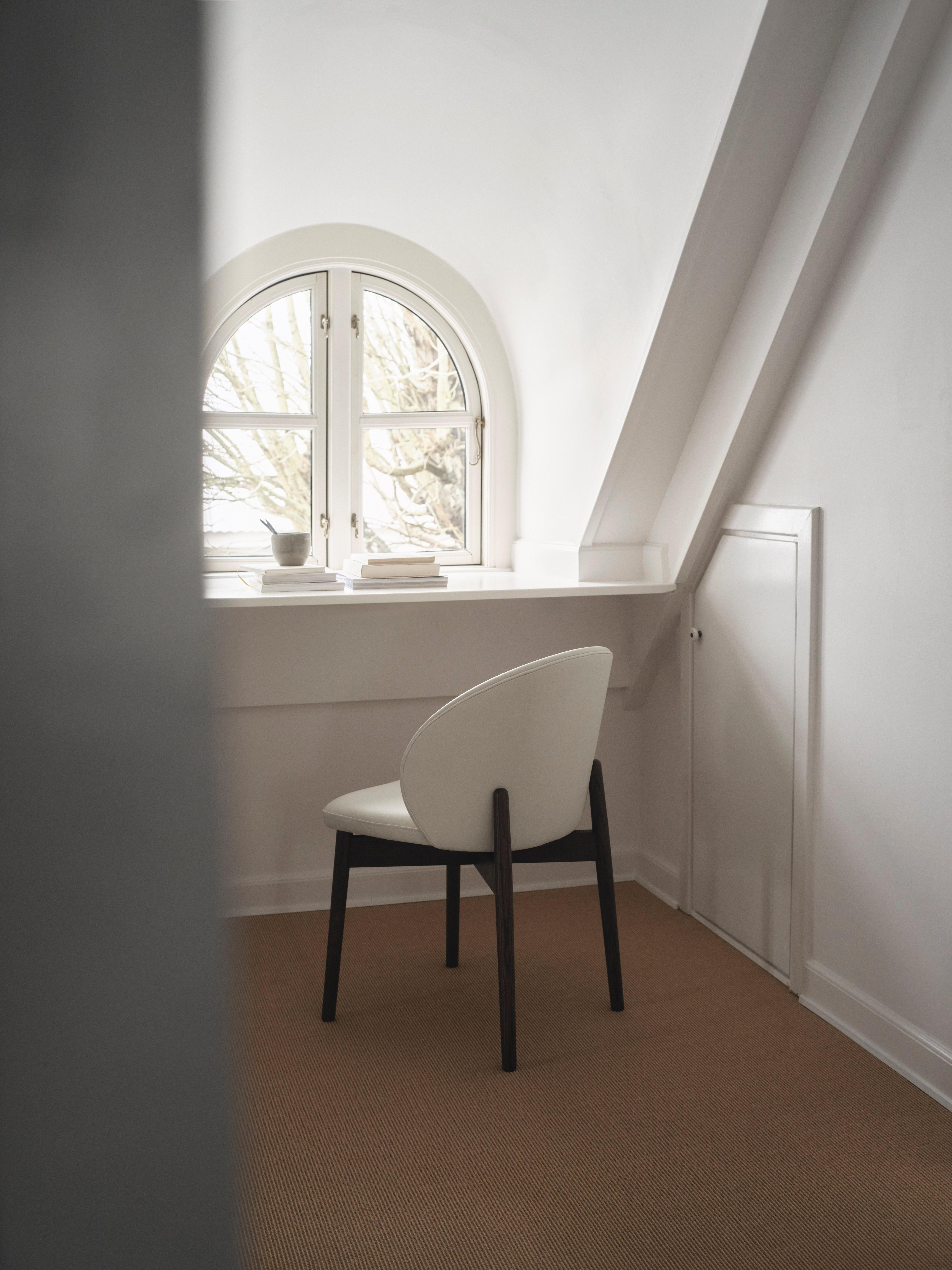 Des chaises modernes dans une pièce avec un mur en bois et des rideaux corail drapés.