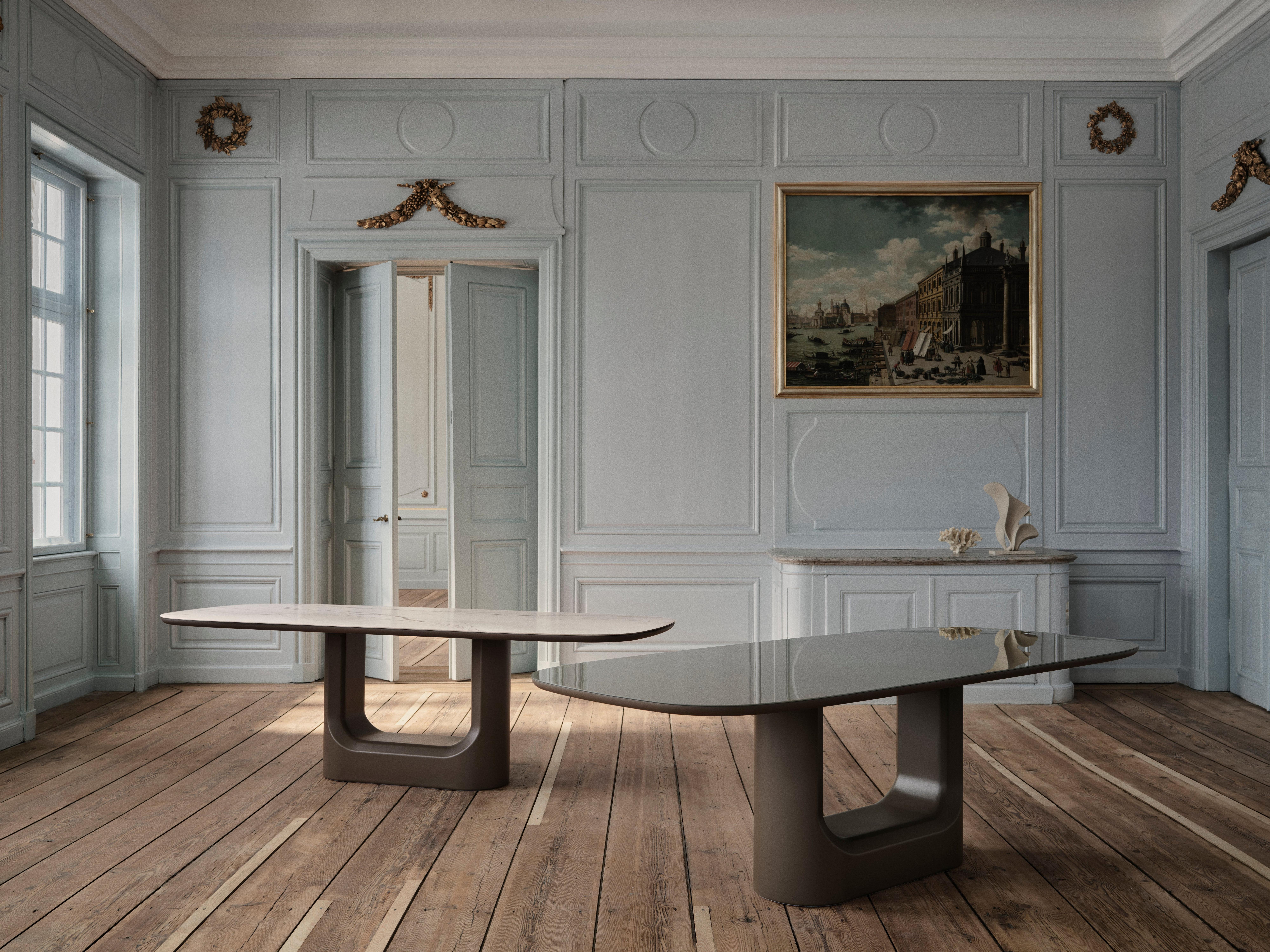 Two modern oval coffee tables with sculptural bases in a classic panelled room.