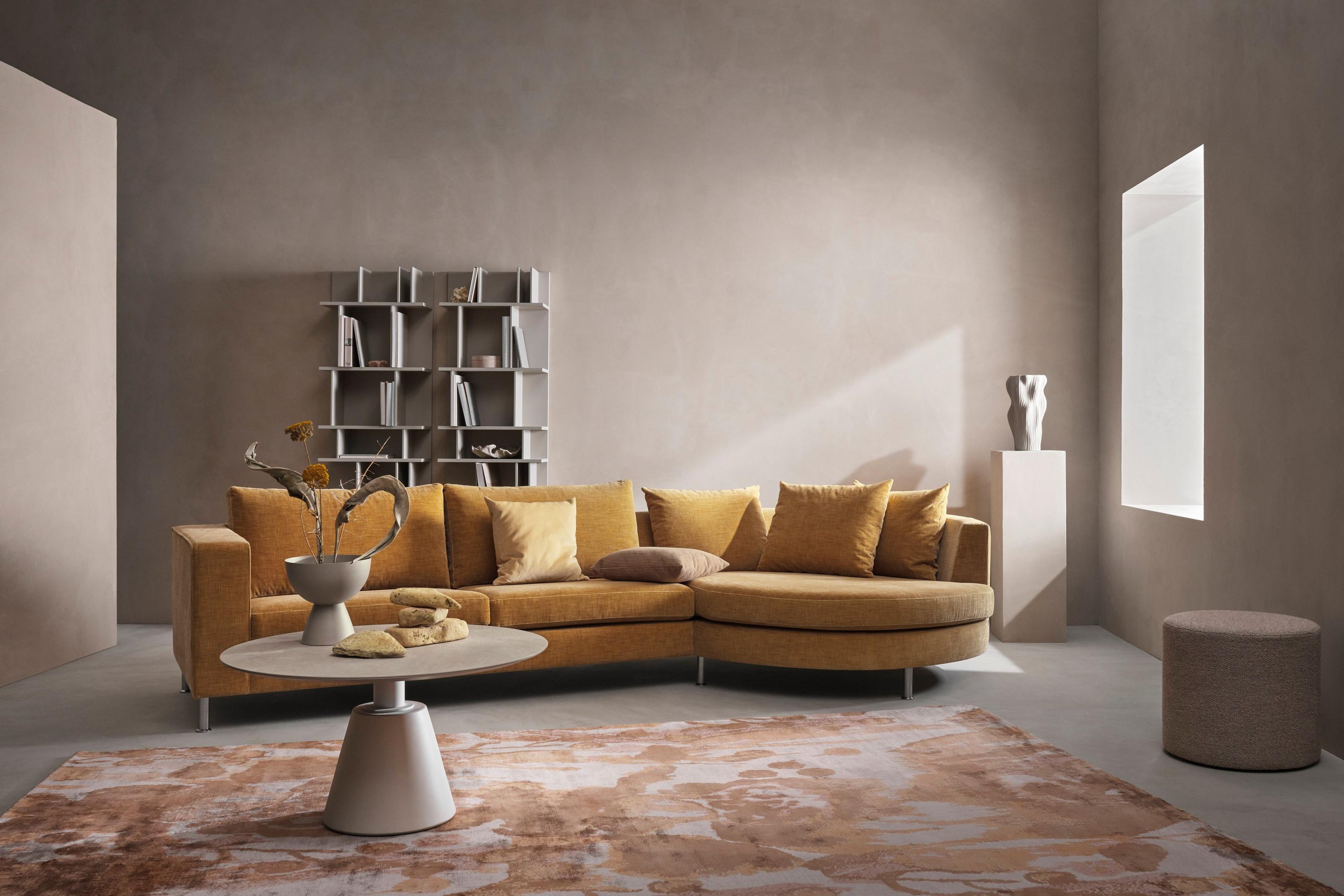 Indivi sofa med rundt hvilemodul i gyldenbeige Napoli stof ved siden af Eden fodskammel og Madrid sofabord.