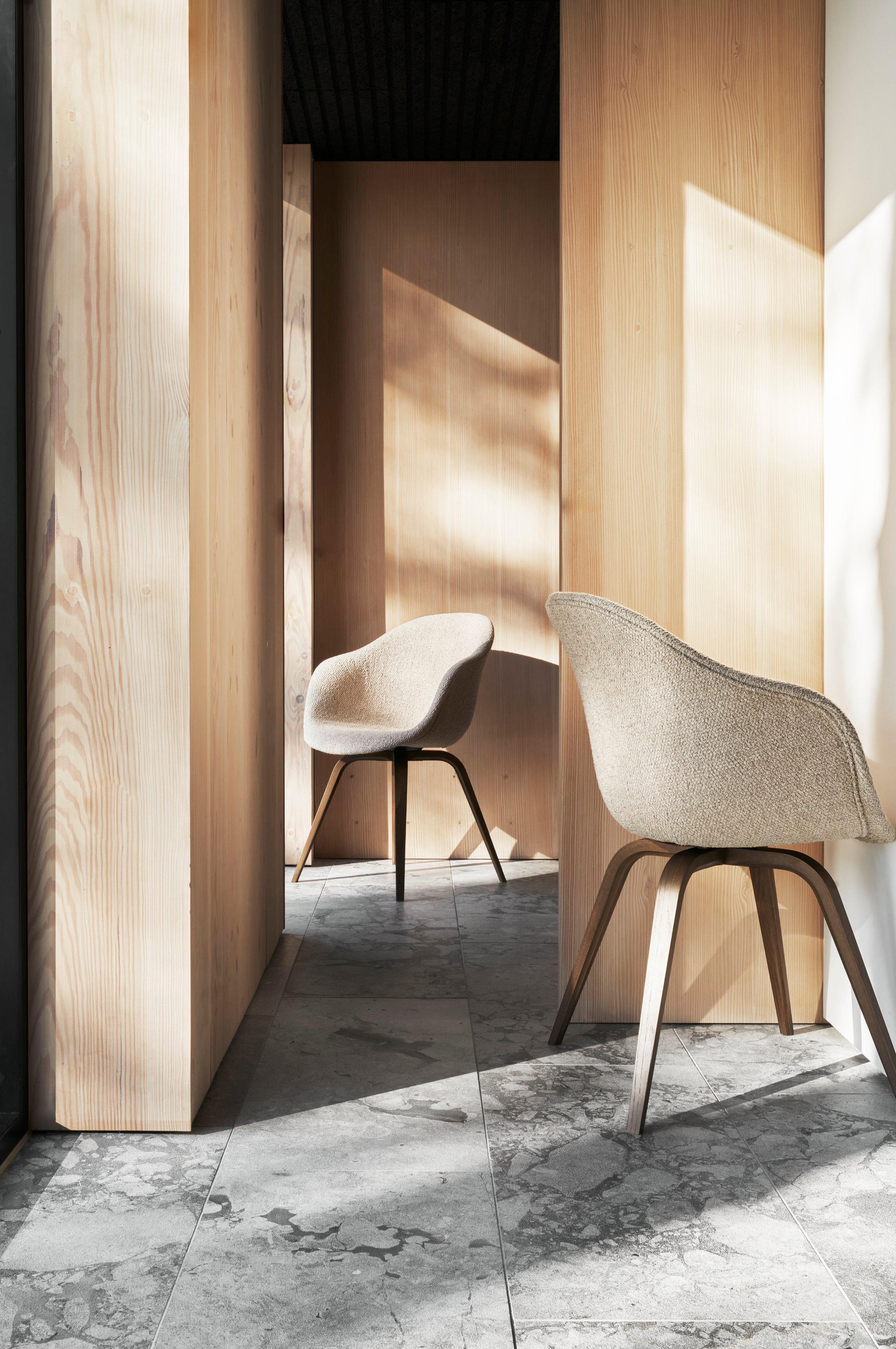 Sunlit interior with two Hauge chairs, wooden walls, and a marble floor.