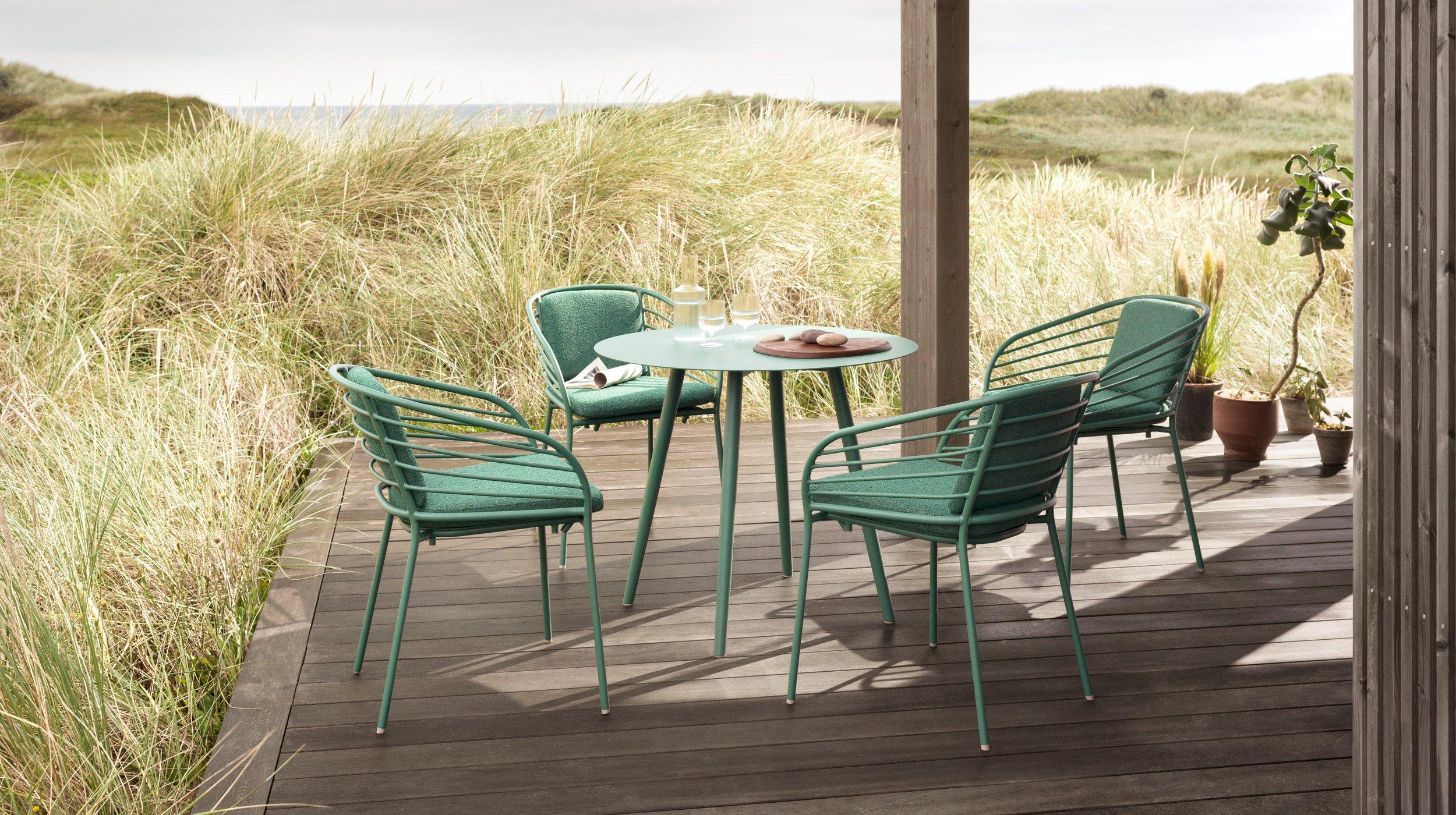 Elegant outdoor entertainment area featuring the Cancún Café table and dining chairs in matt green.