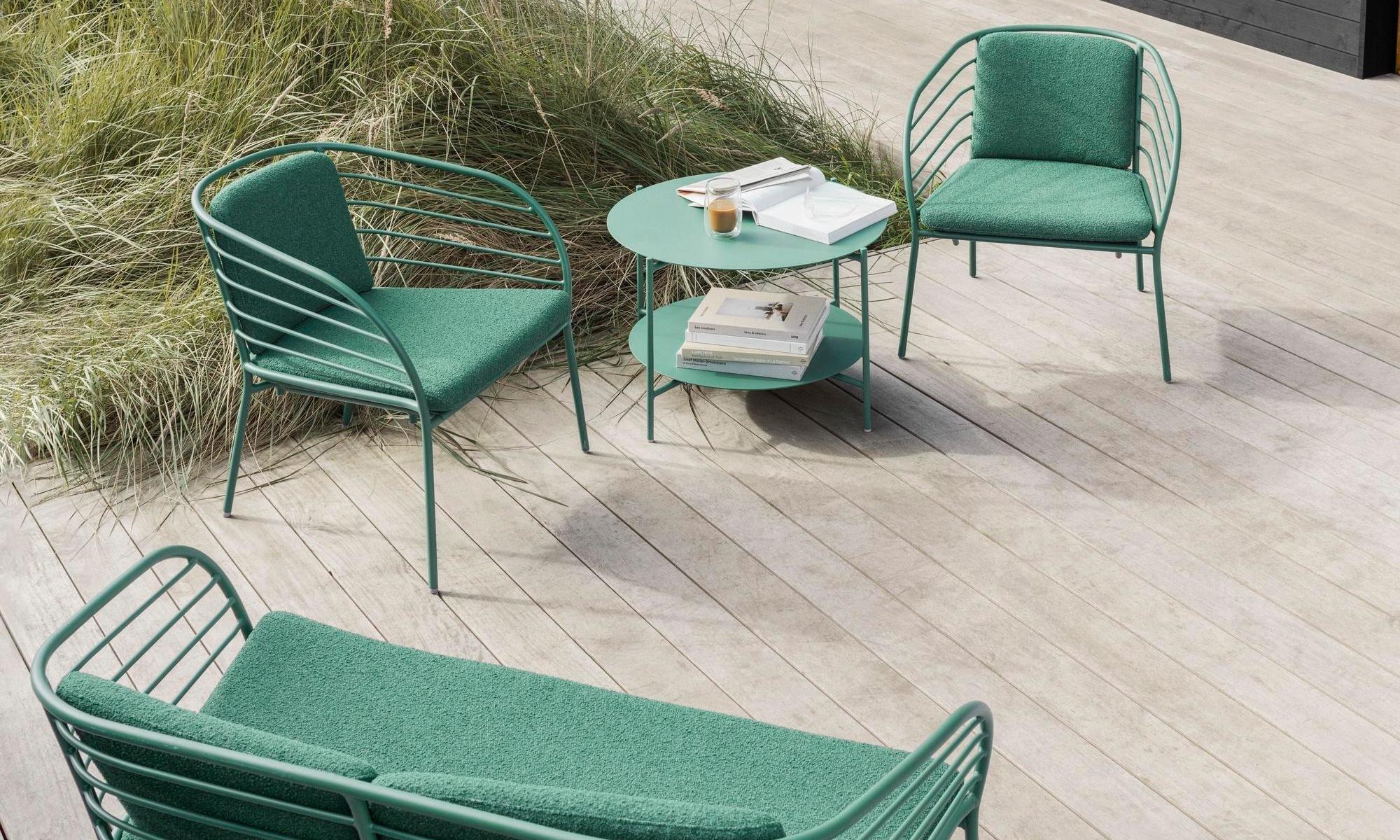 The Cancún lounge chair and café table, along with the Cancún lounge sofa, on the back deck of a modernist summer house.