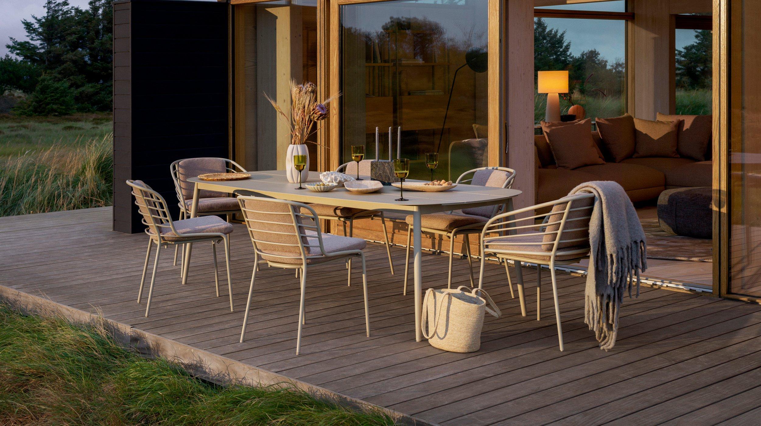Outdoor dining area with table, chairs, and decor; cozy indoor living space visible.