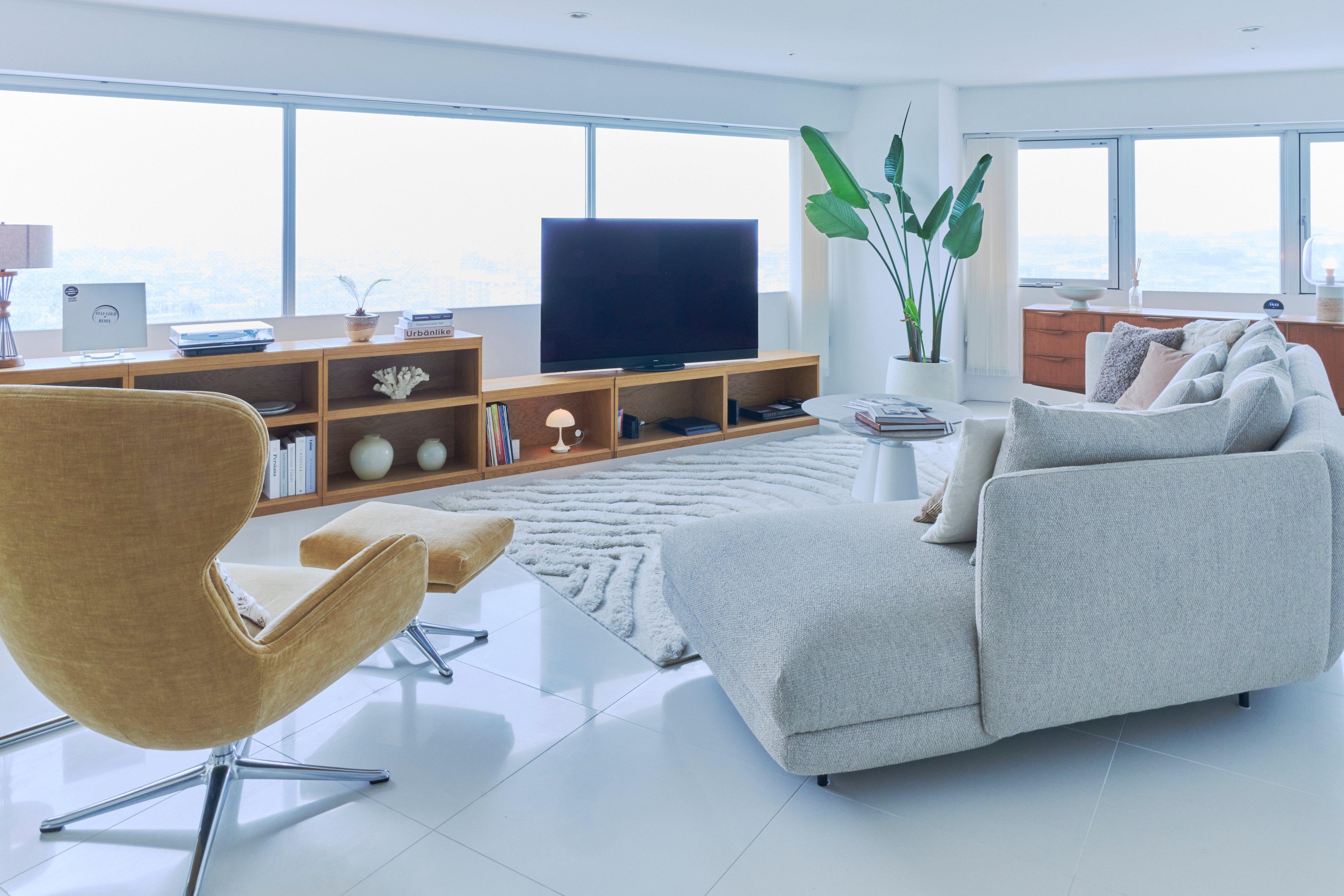 Modern living room with grey sofa, armchair, TV on wooden unit, and coffee table.