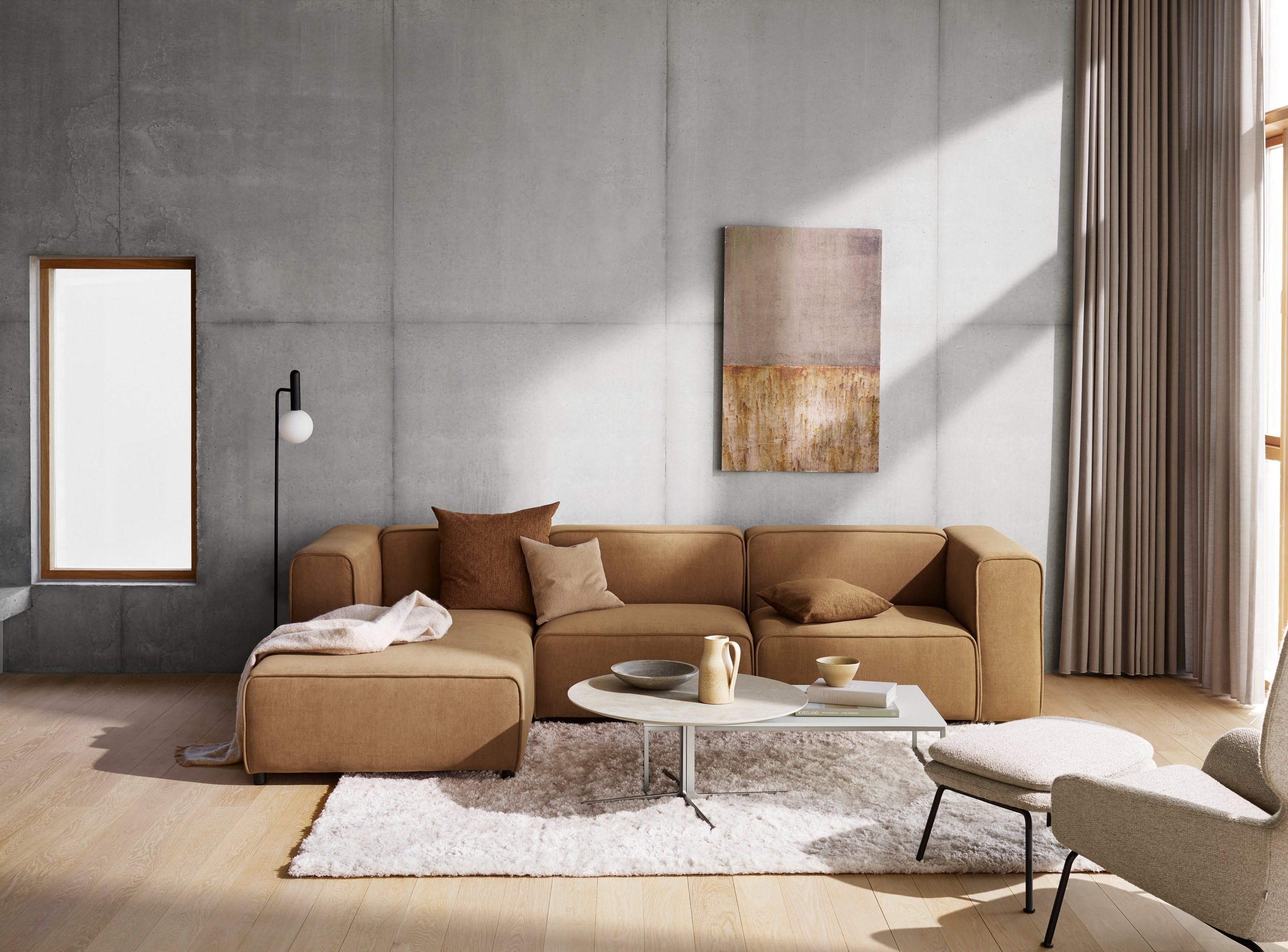 Un salon moderne avec un canapé modulable beige, une décoration murale abstraite et un tapis moelleux sur un parquet.