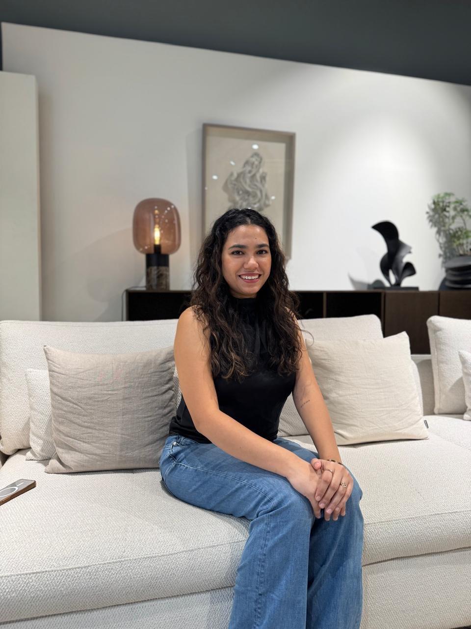 Woman sitting on a light fabric sofa with matching cushions.