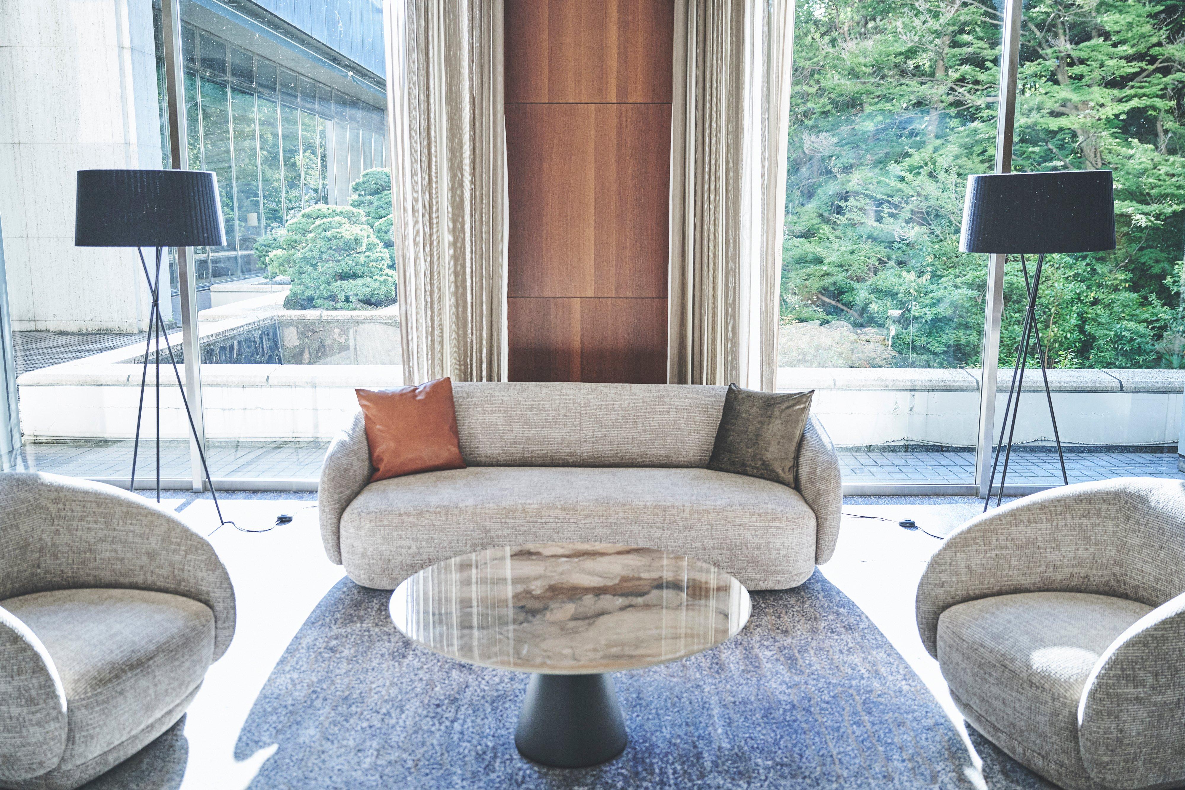 Modern lounge with grey sofa and armchairs, marble-top coffee table, and two floor lamps.