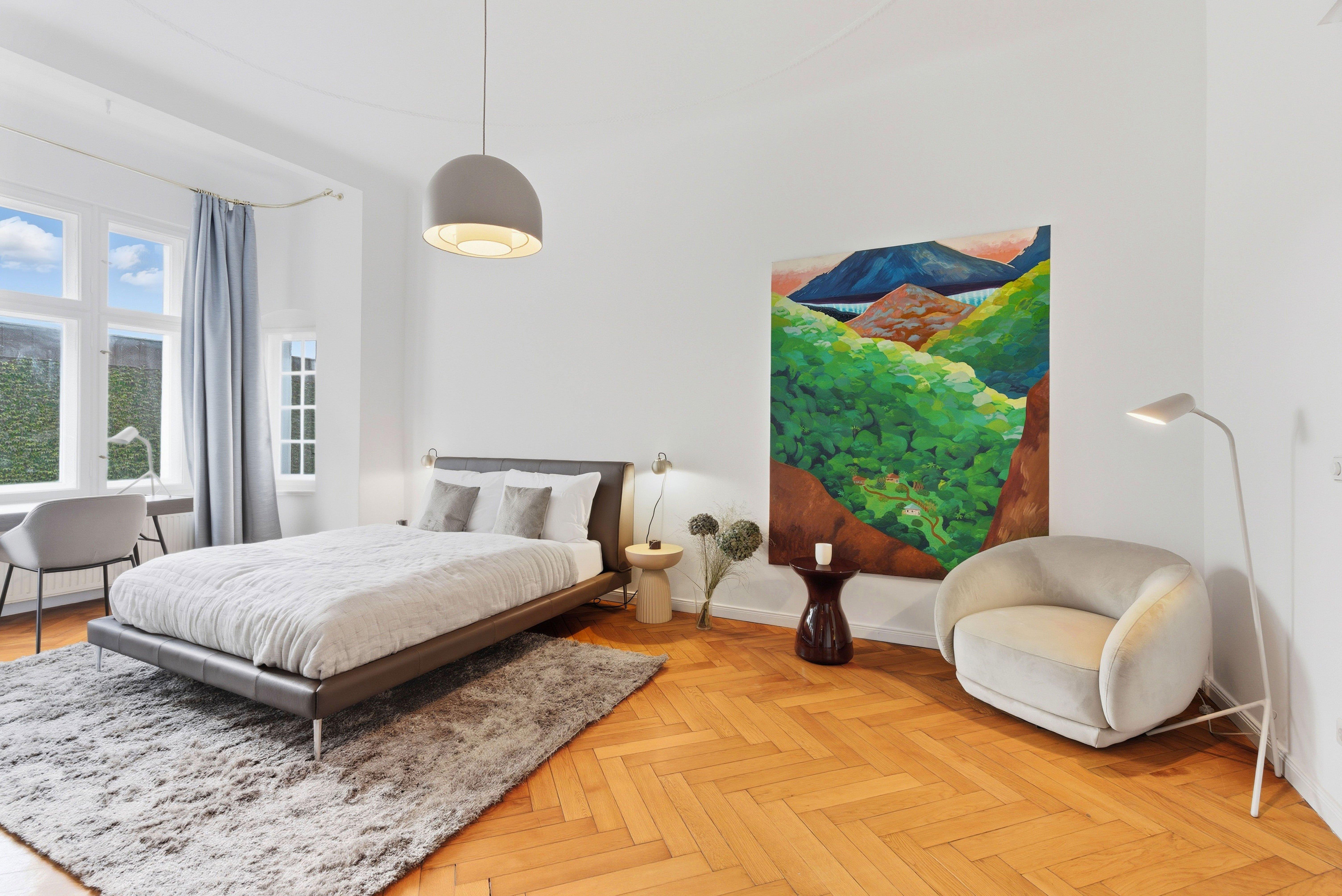 Chambre moderne avec lit, tableau coloré, fauteuil et fenêtre lumineuse.