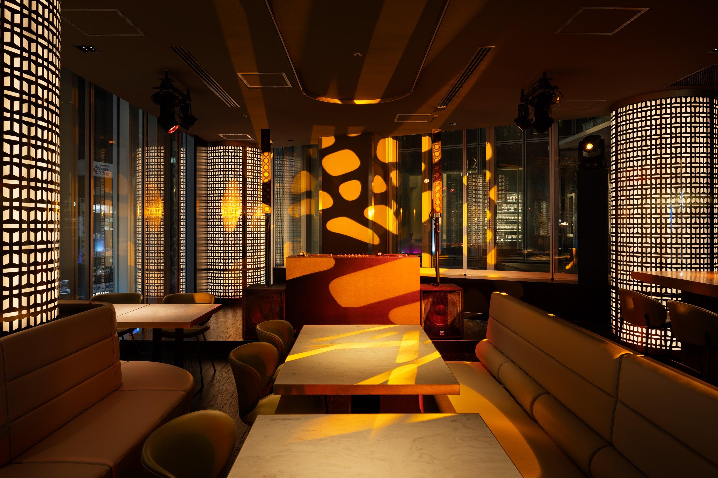 Interior de un bar con luces amarillas y patrones en las paredes y mesas.