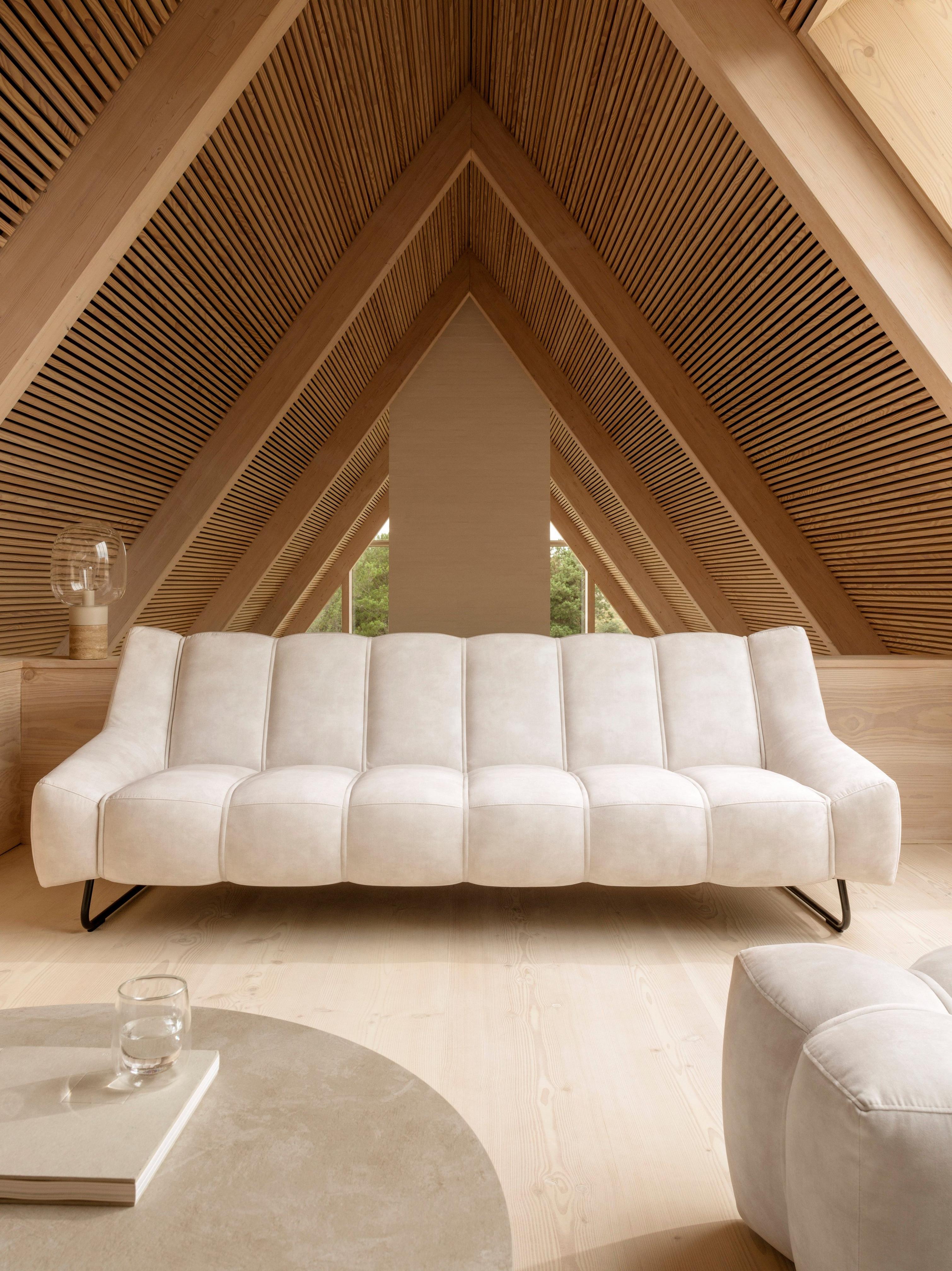 三角形の天井を持つニュートラルなリビングルームに、ベージュのRavello ファブリックを使った3人掛けのNawabari ソファを配置したスタイリング。