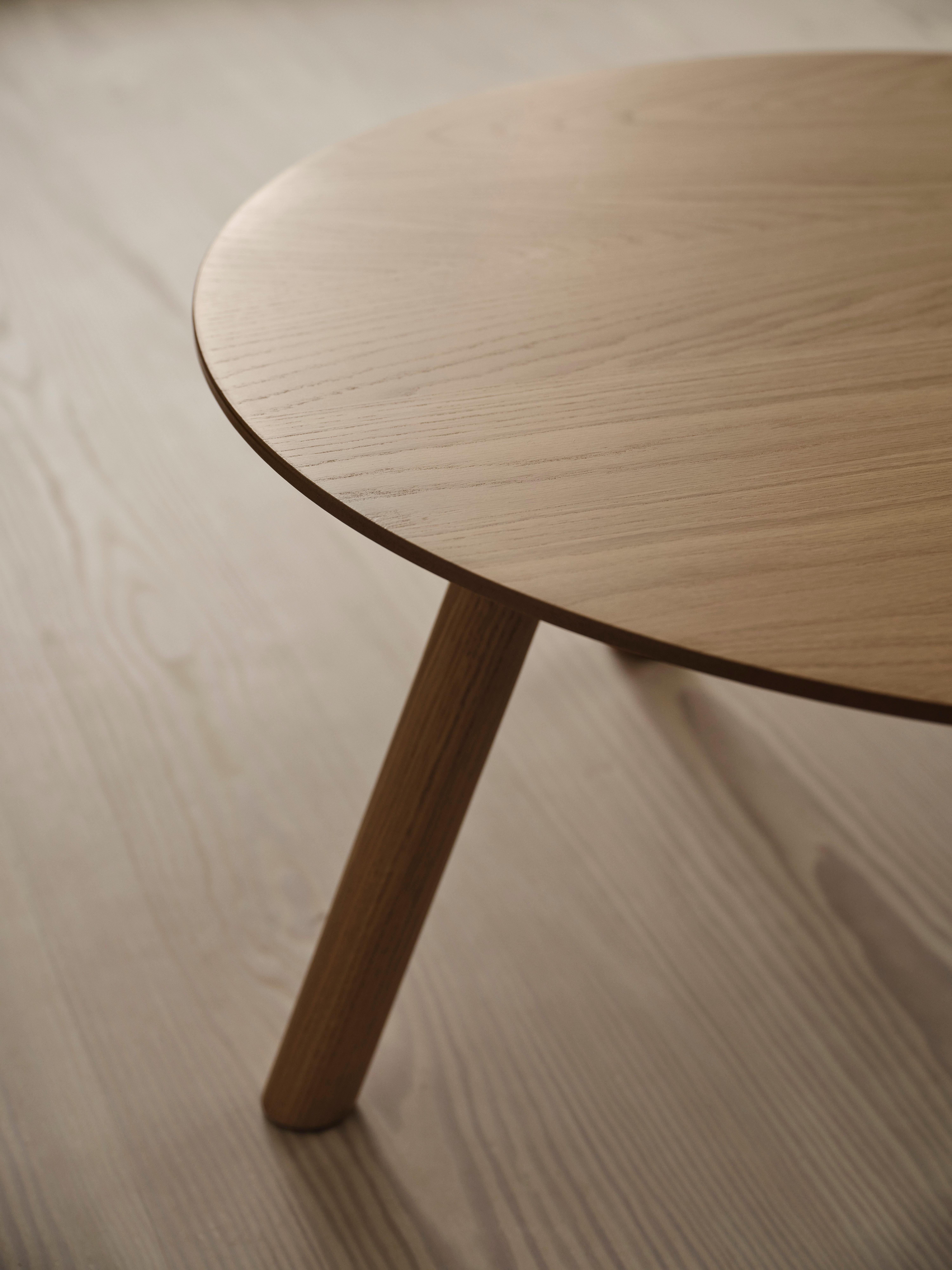 Pyöreä puinen pöytätaso ja jalka vaalealla lattialla.
