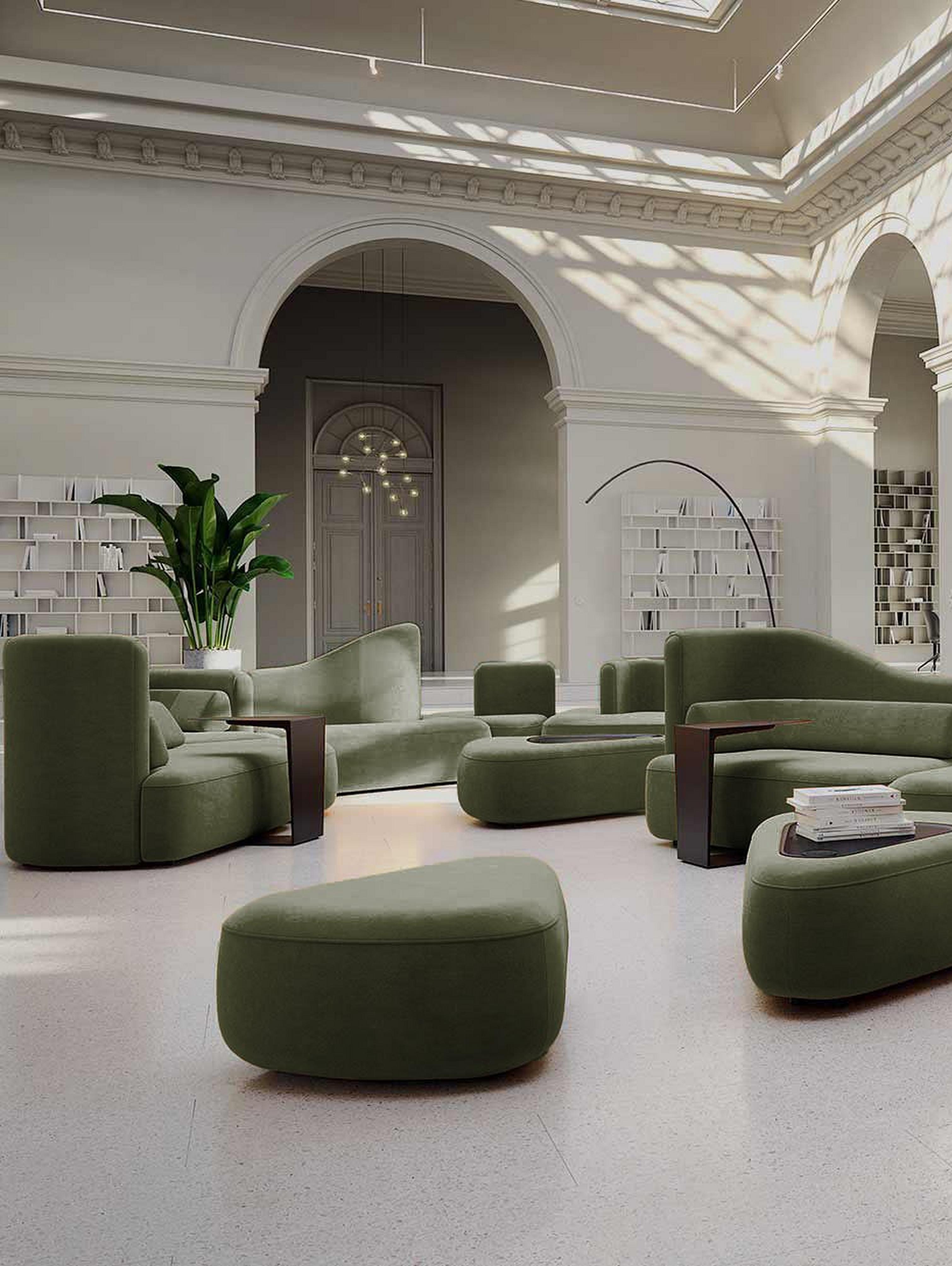 Spacious room with green sofas, white columns, arches, and potted plants in a bright setting.