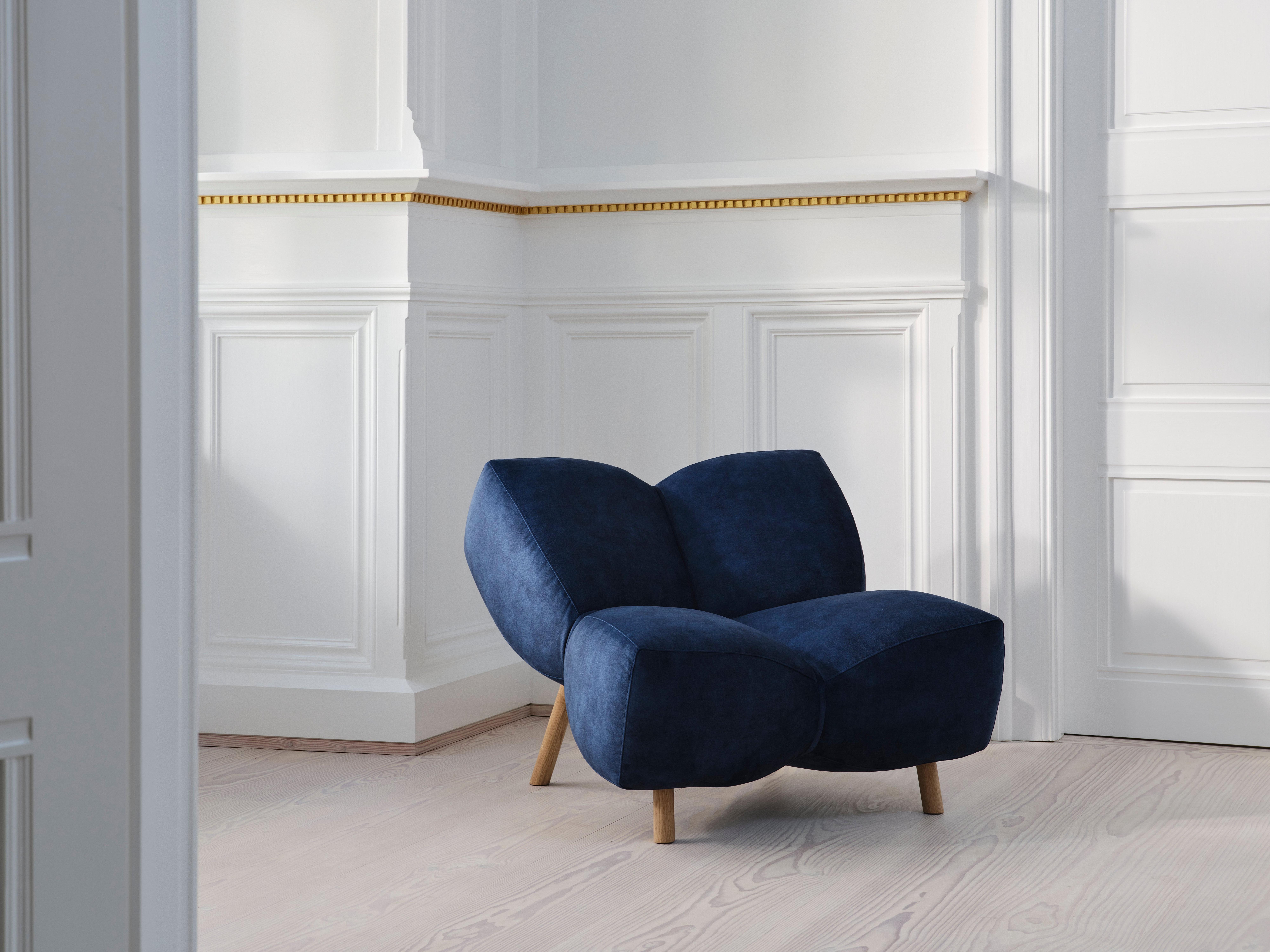 Tummansininen nojatuoli vaalealla puulattialla, valkoisten seinien vieressä.