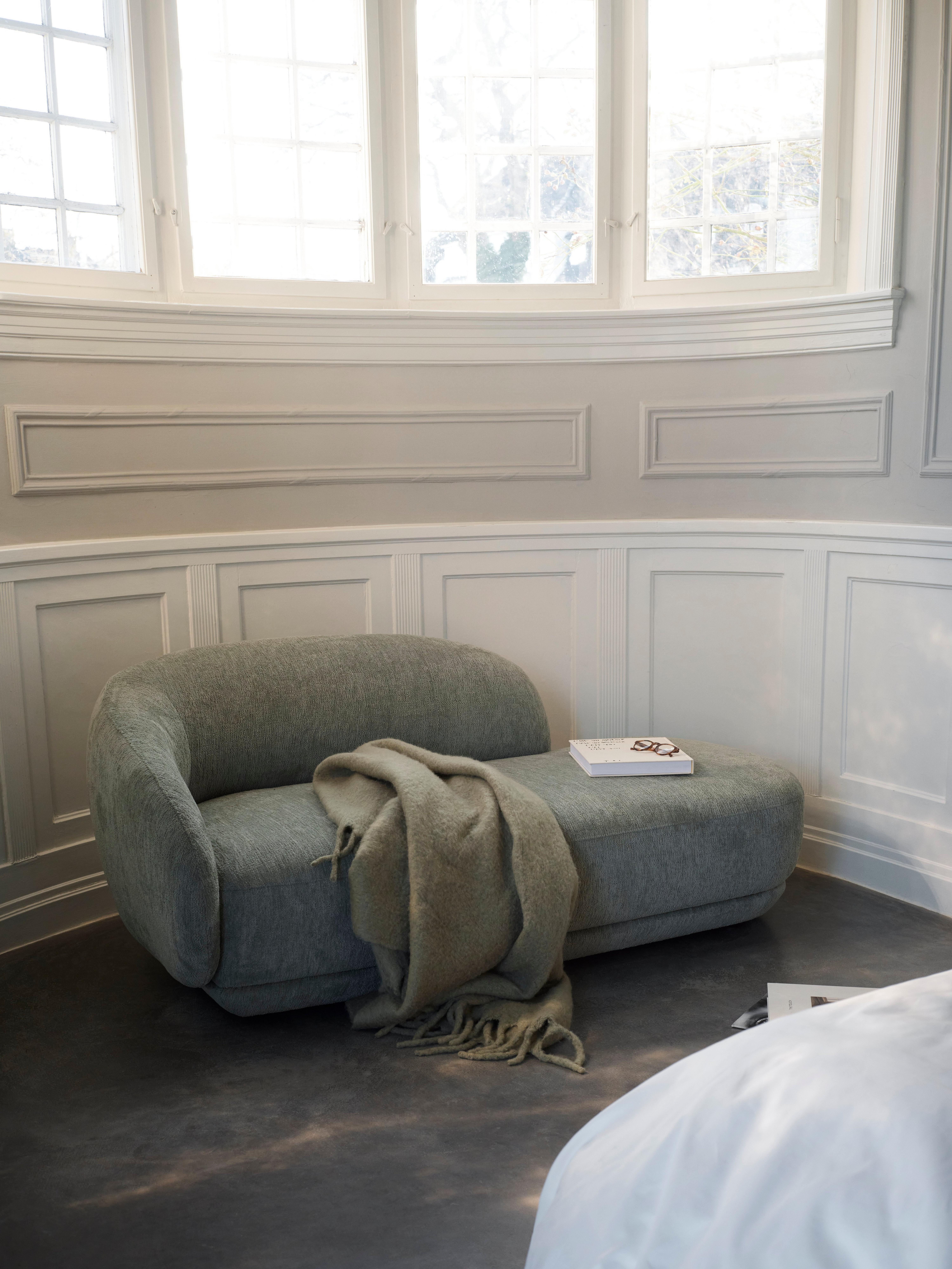 Bolzano chaise longue sofa right in green Lucca fabric near a curved window, alongside Bolzano bed with slats W180xL200cm in beige Lucca fabric.