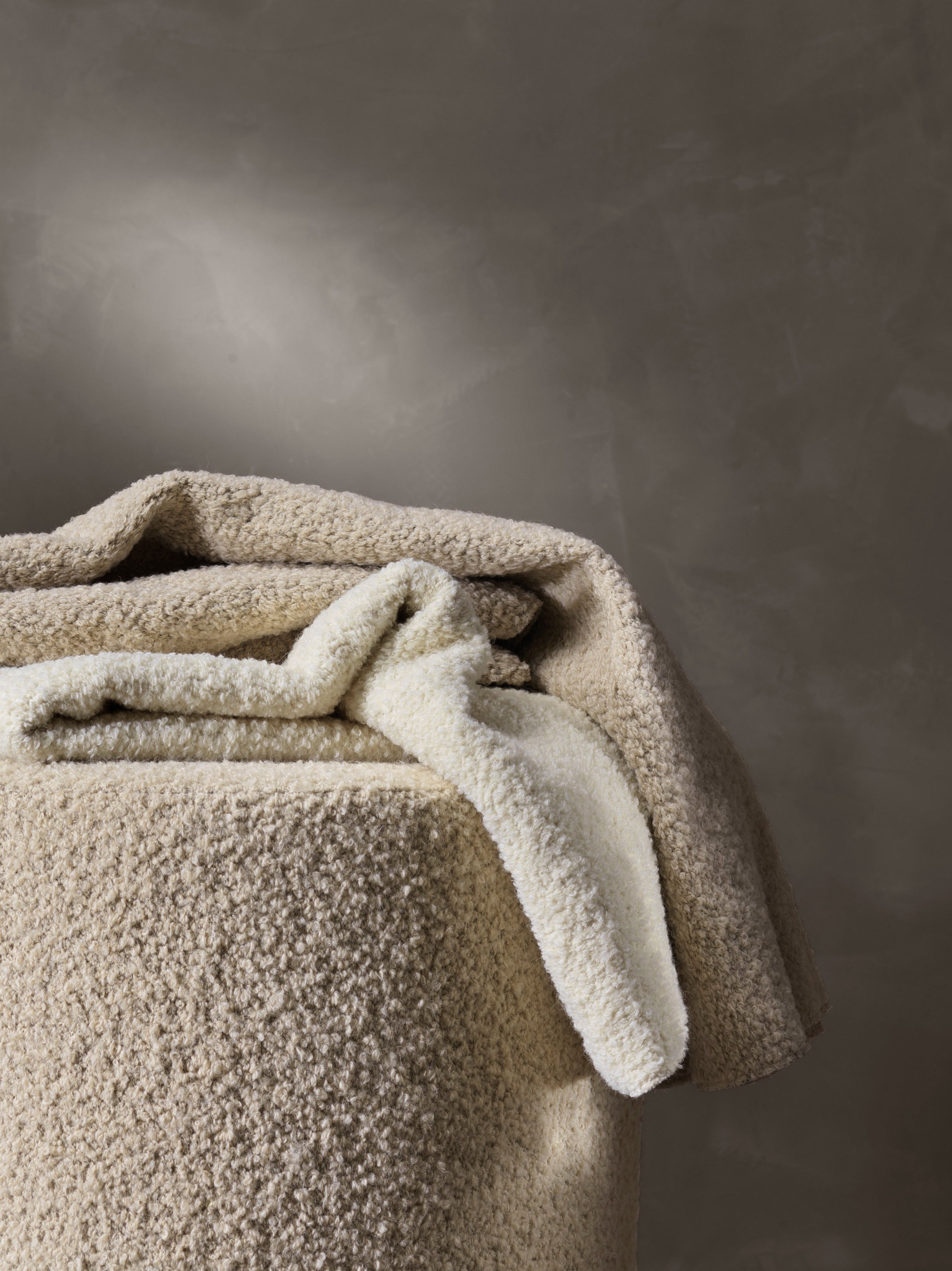 Textured bouclé fabric draped over an object with a soft, plush appearance.