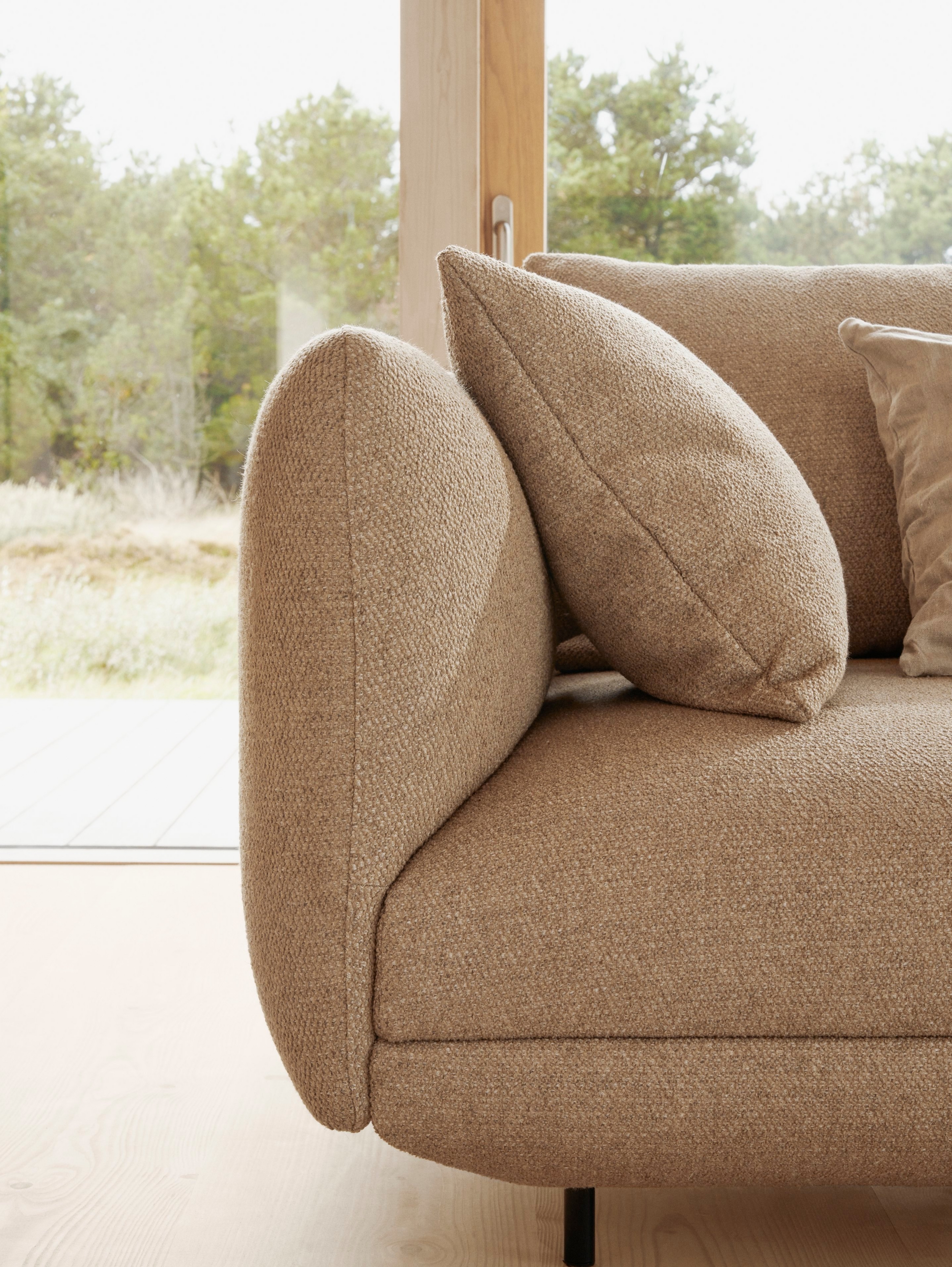 A close-up view of the armrest of the Salamanca sofa in a sunlit living room.
