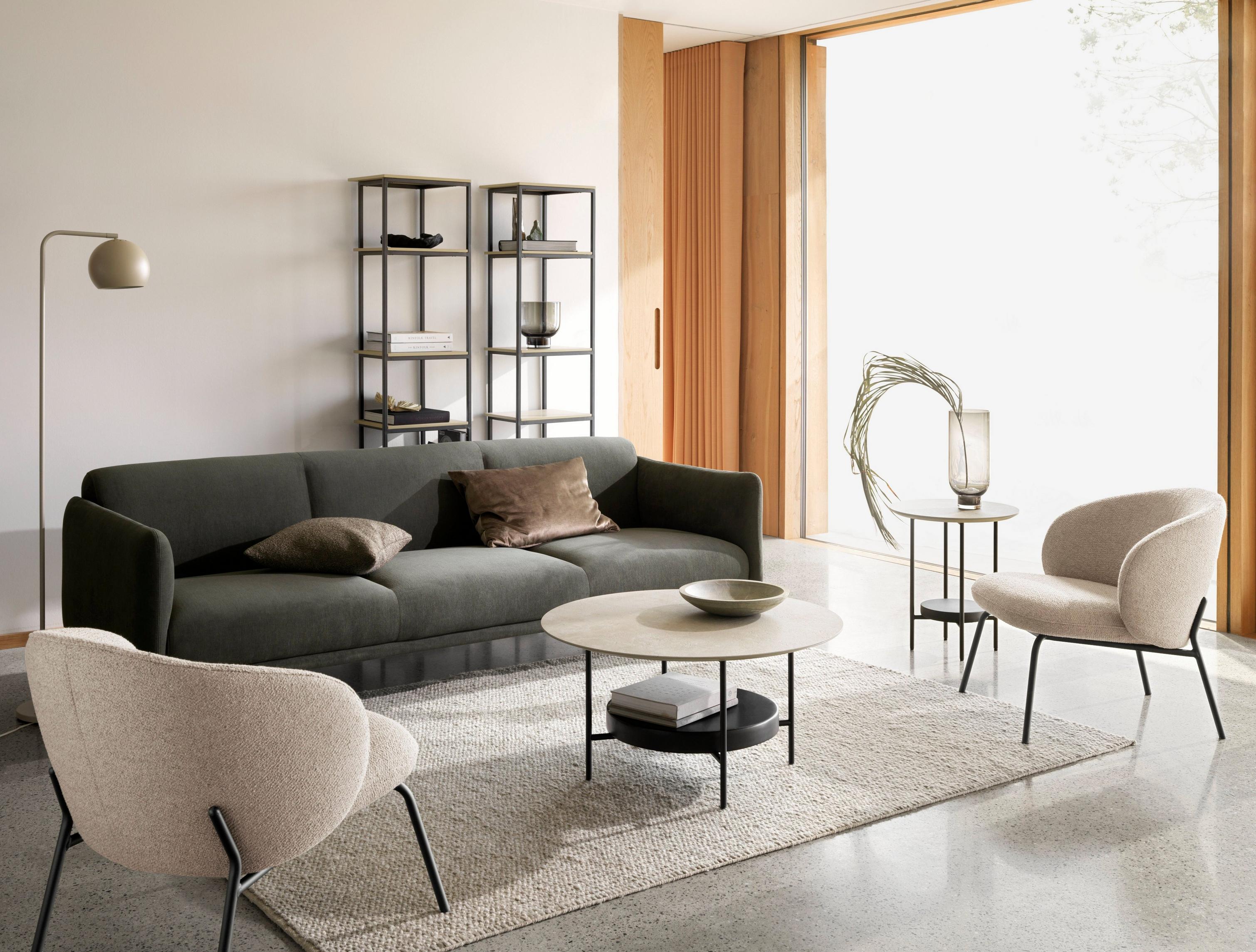 3-osobowa sofa Berne tapicerowana ciemnozieloną tkaniną Frisco, stolik kawowy Madrid i fotel Princeton w beżowej tkaninie Lazio.