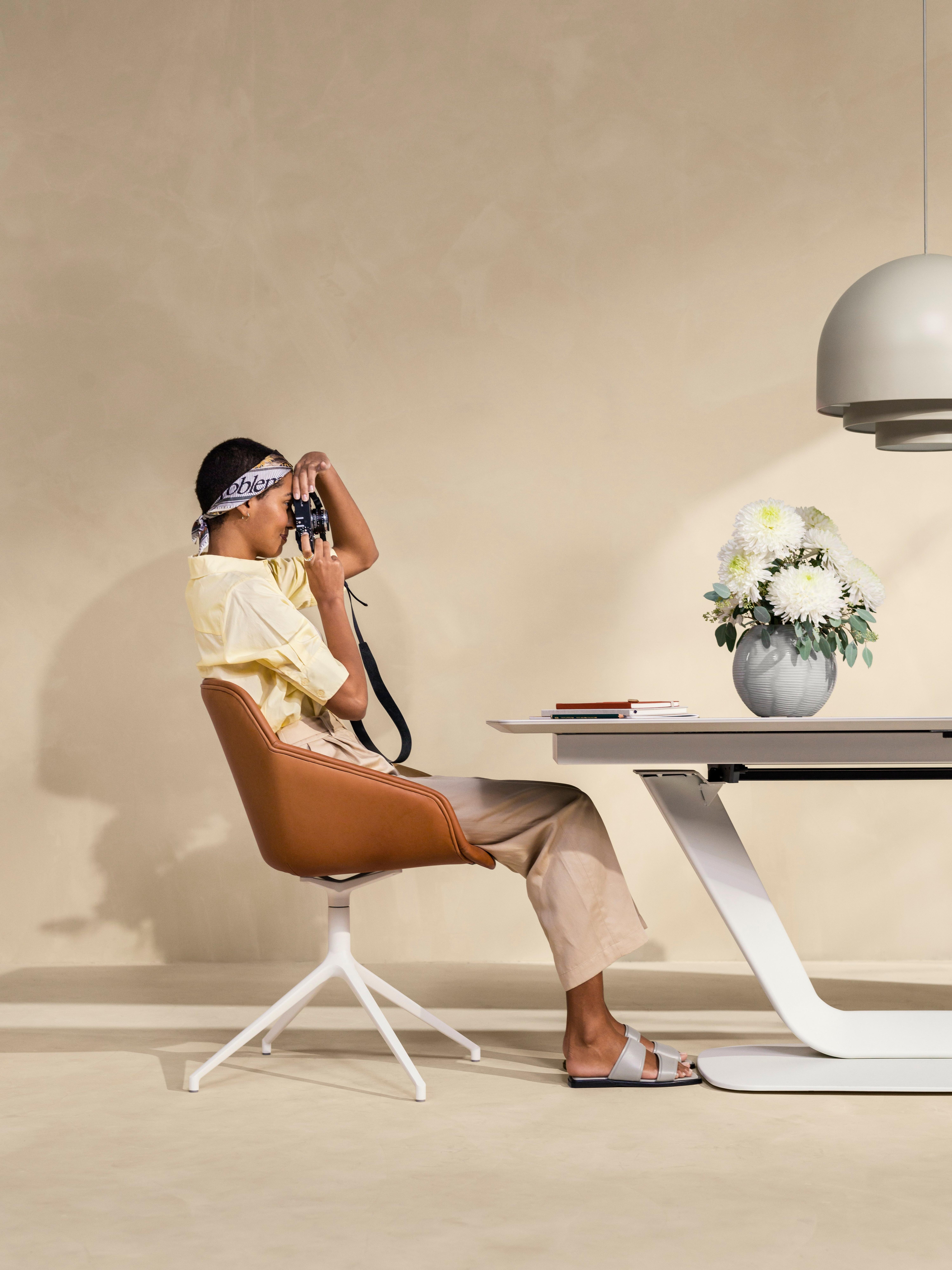 Woman taking photos at the Alicante dining table in ash ceramic.