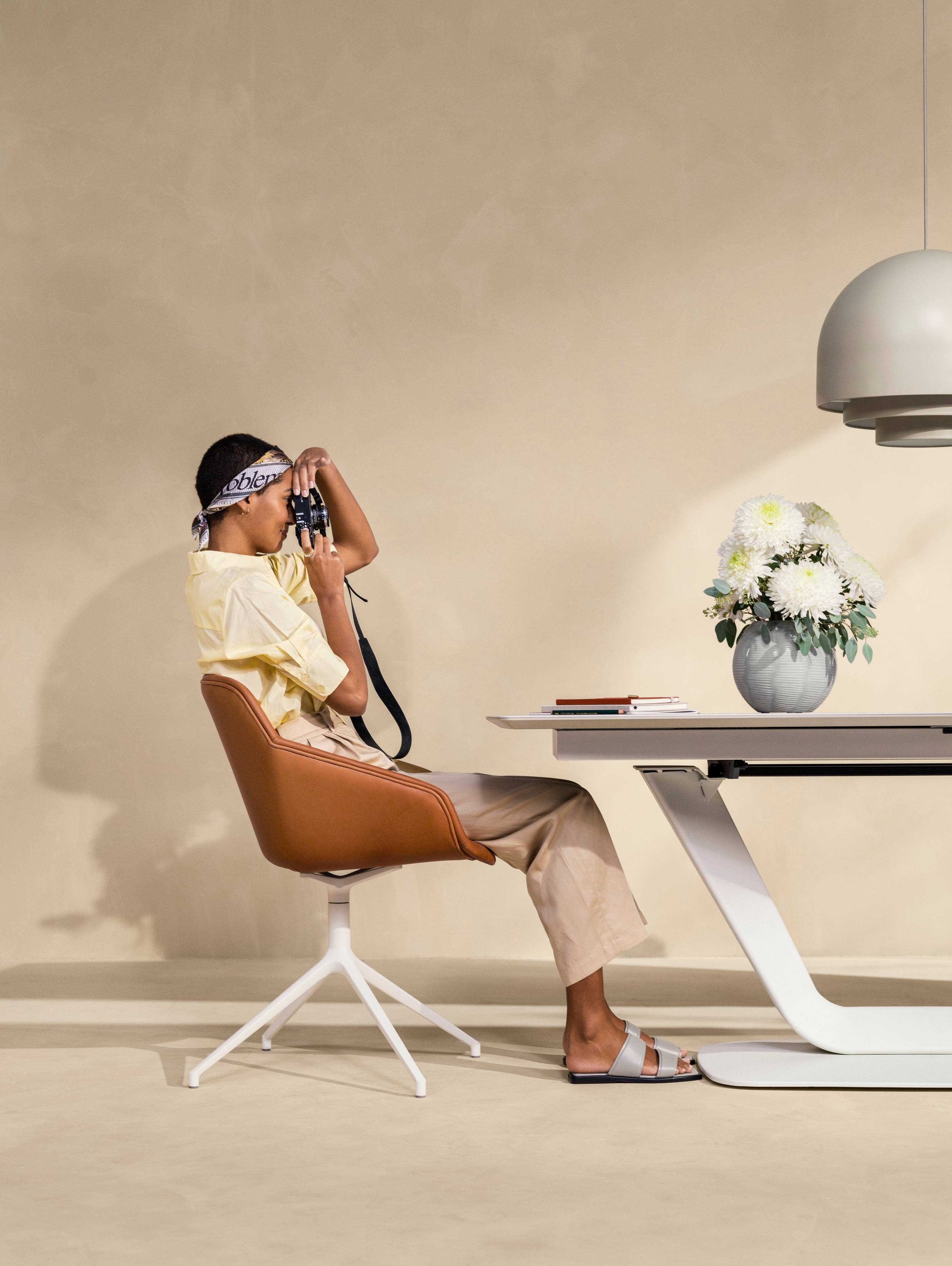 Woman taking photos at the Alicante dining table in ash ceramic.