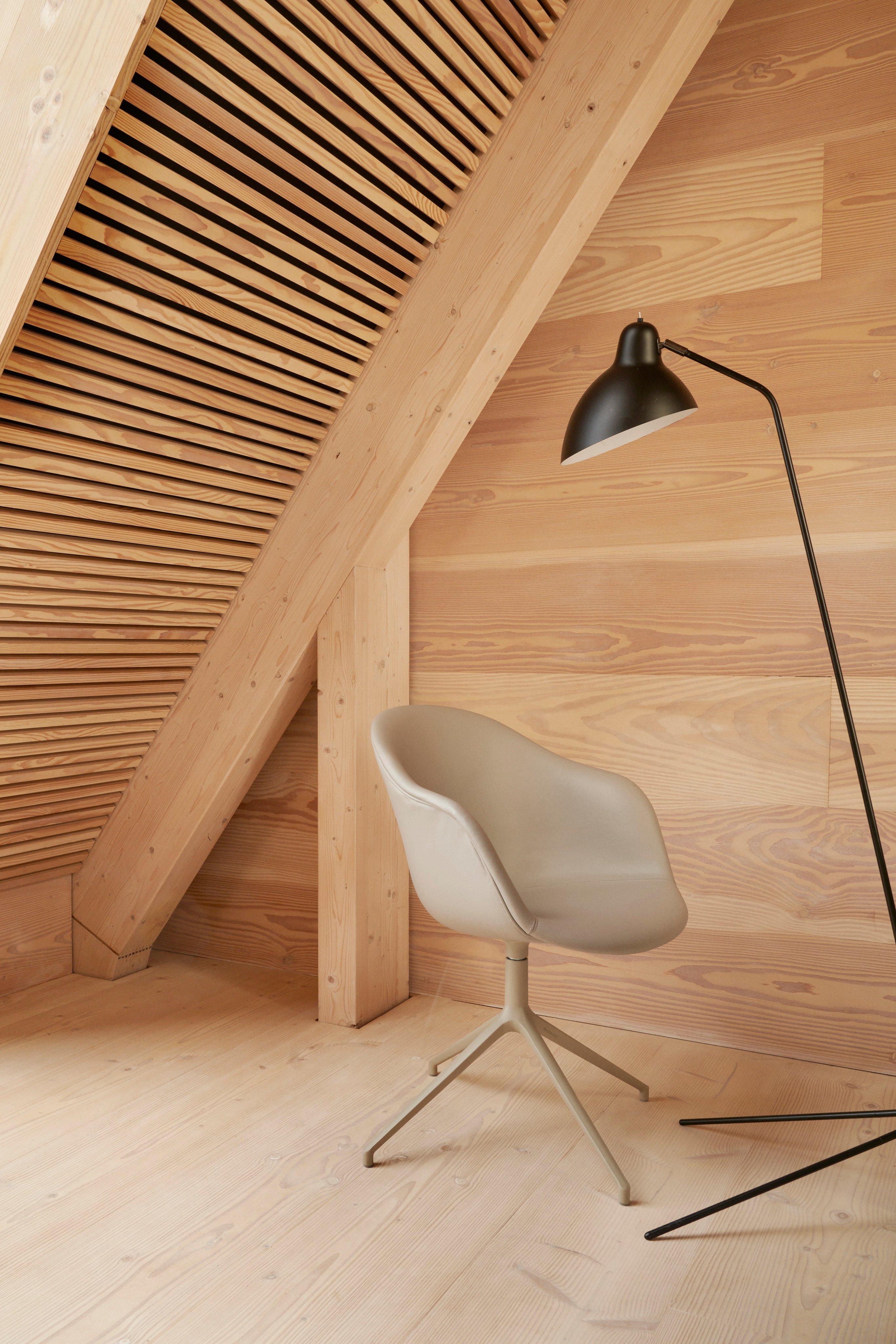 The Adelaide chair upholstered in light taupe Estoril leather in a corner with the Demand floor lamp.