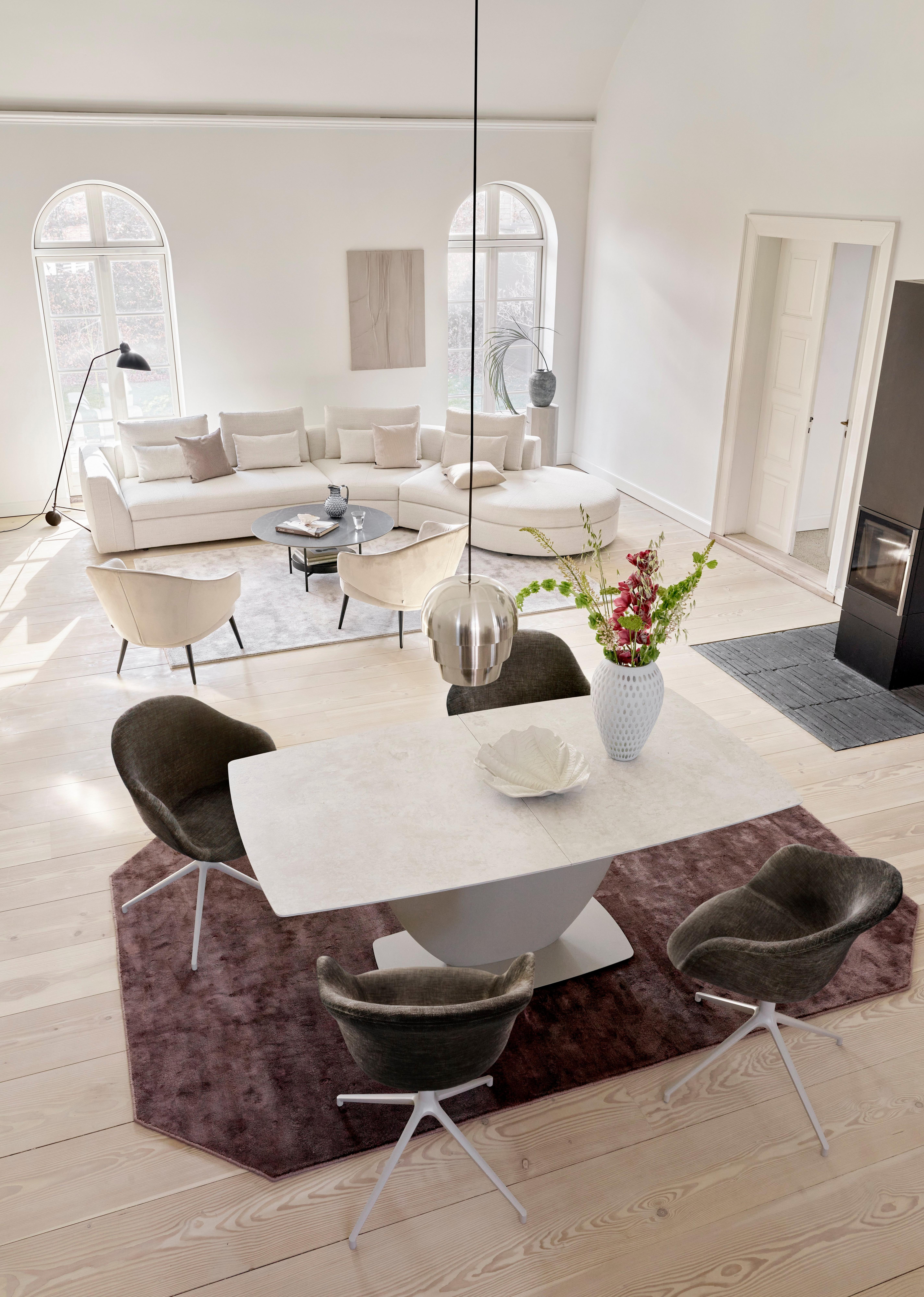 Elegantní jídelna s mramorovým stolem, sametovými židlemi a bílou pohovkou v pozadí.