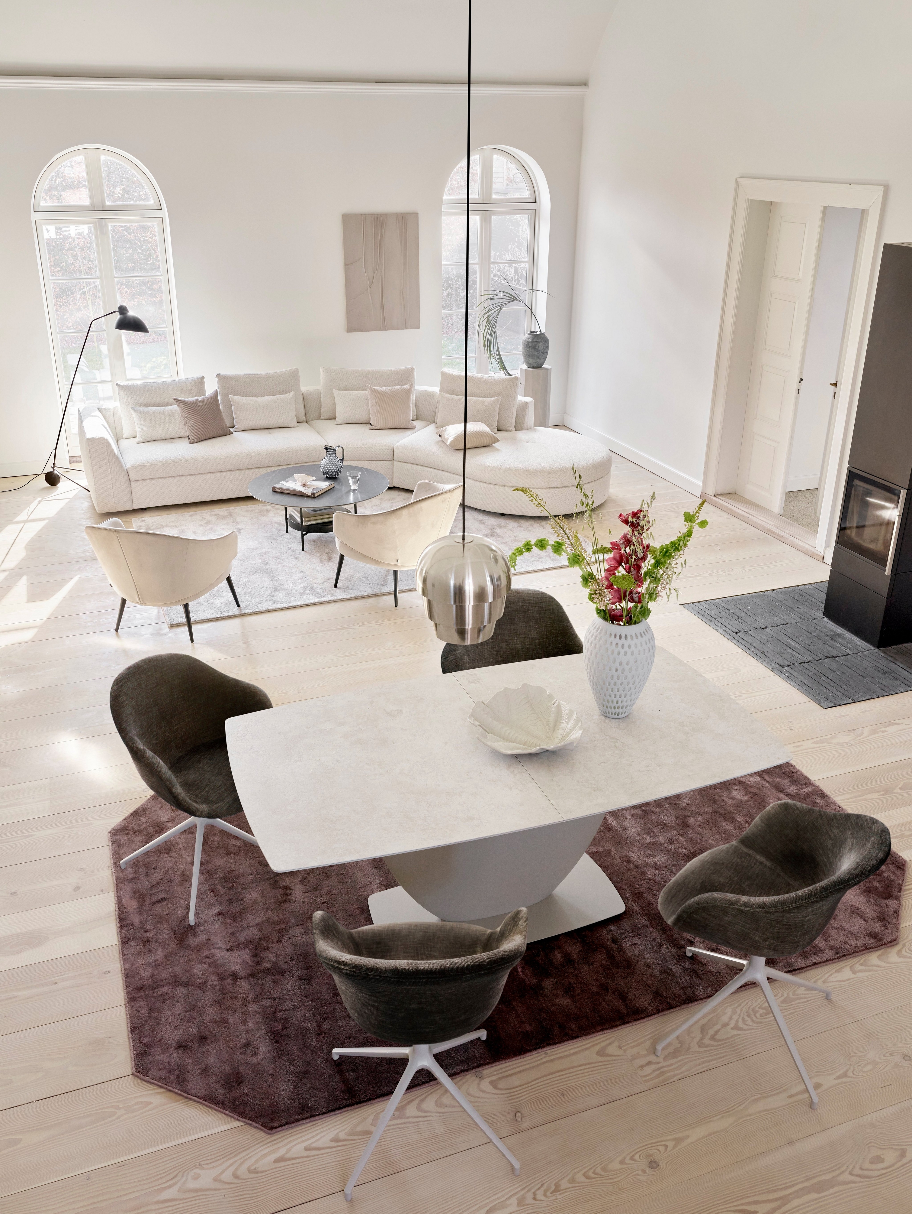 Elegant spiseområde med marmorbord, stole polstret med velour og hvid sofa i baggrunden.