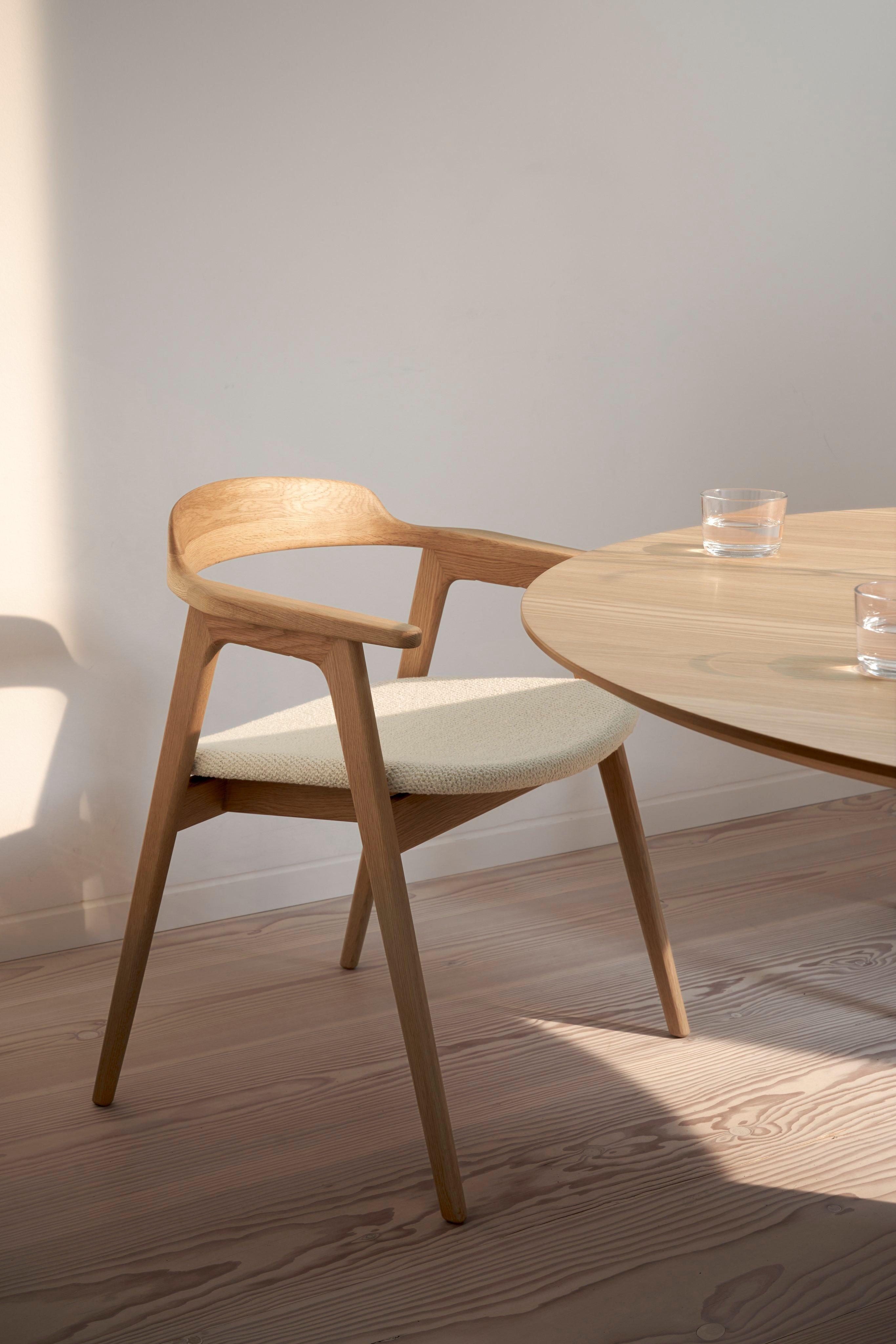 Chaise en bois design avec assise rembourrée près d'une table ronde. Verres sur la table.