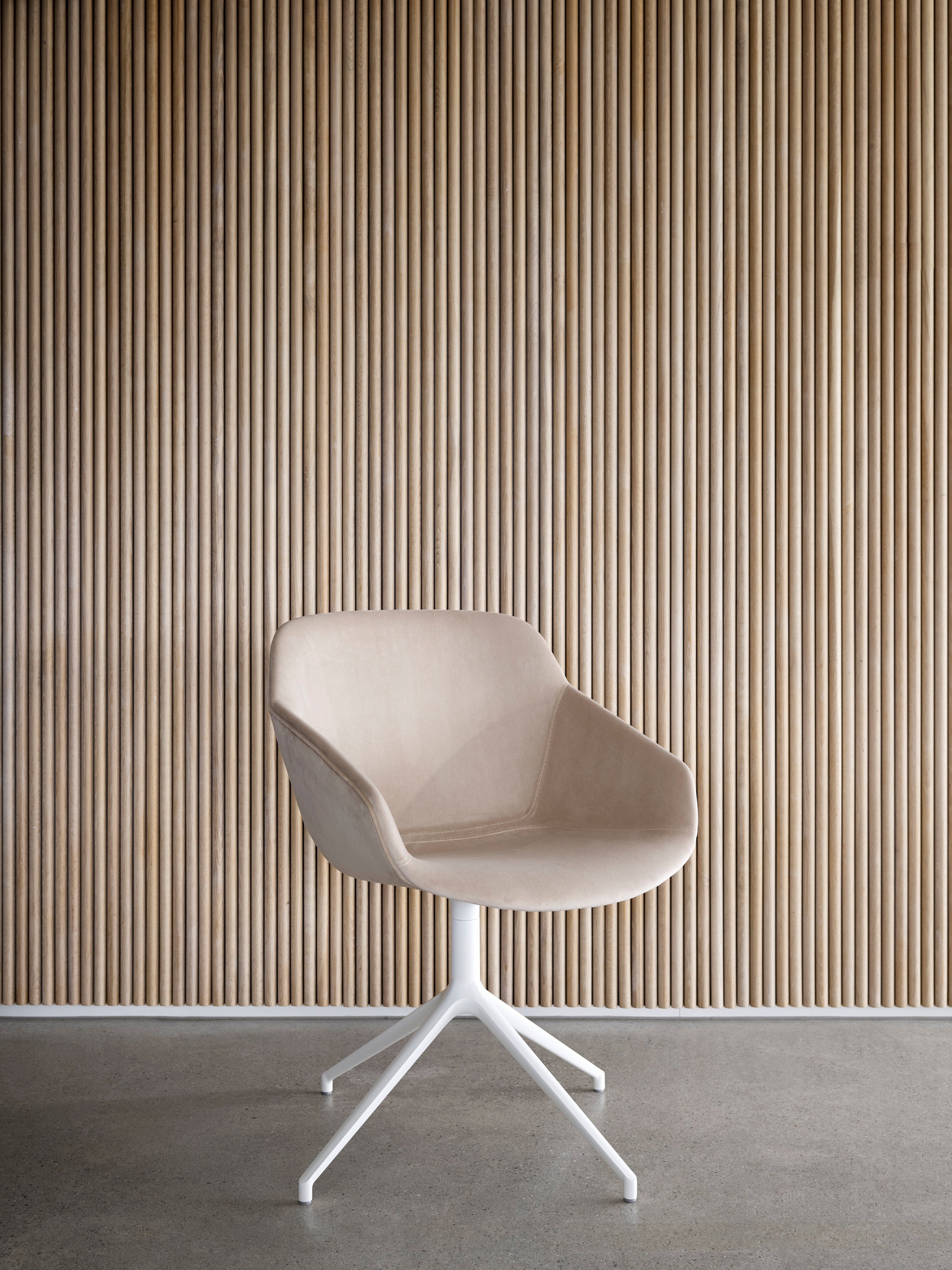 Béžová stolička s bielou podnožou pri vertikálnej drevenej lamelovej stene.