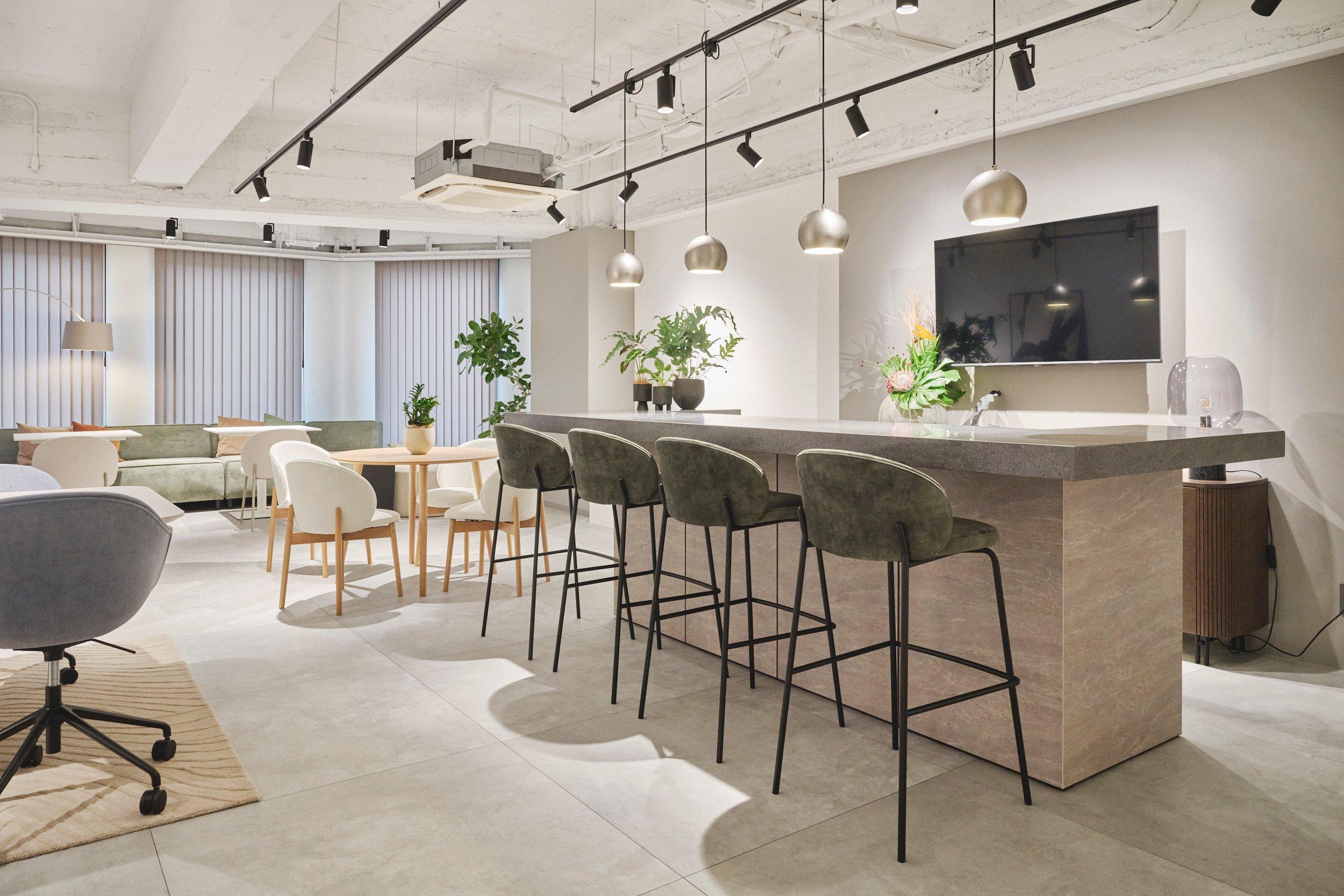 Sala moderna con barra de desayuno, sillas altas, mesa redonda y plantas decorativas.