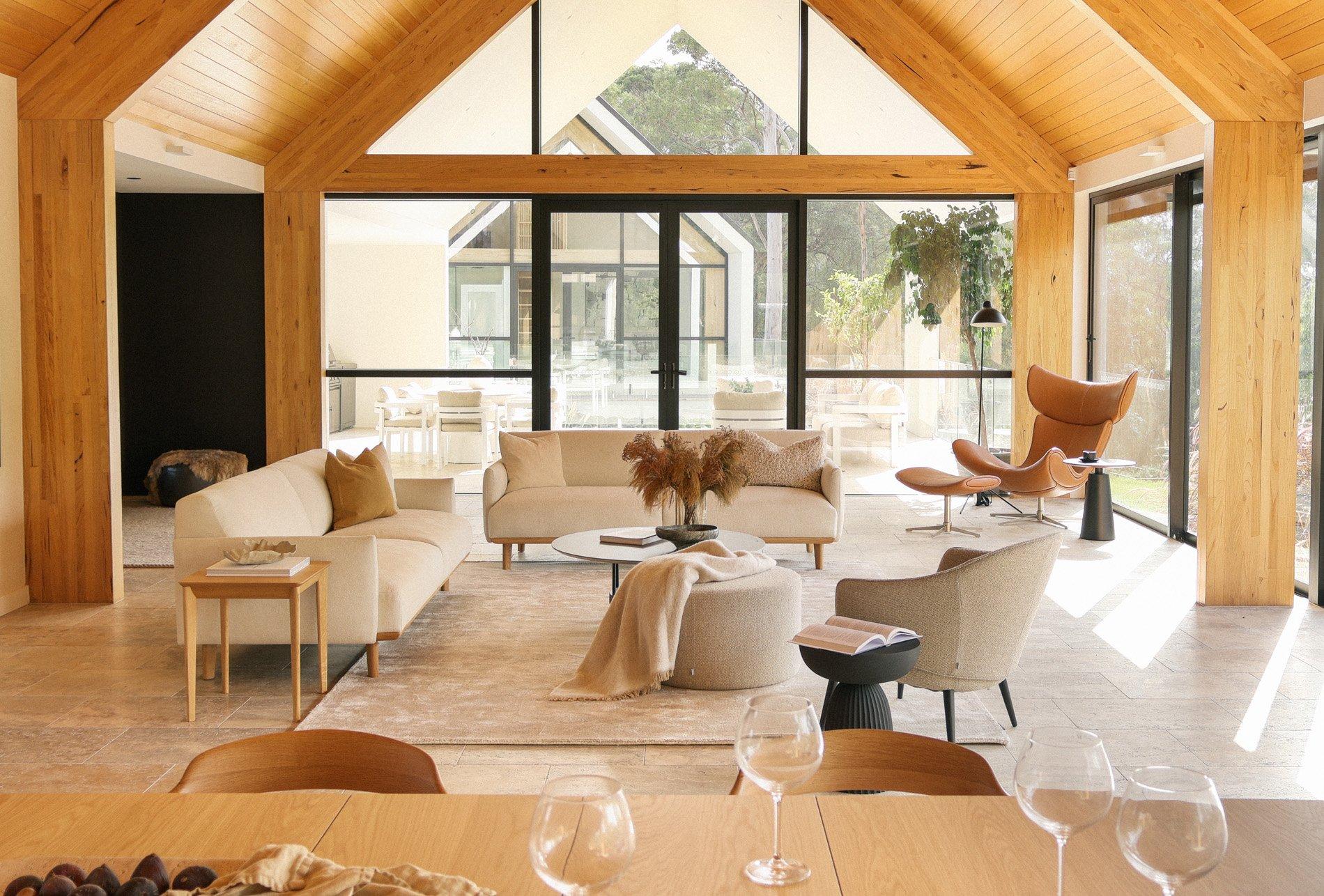 Modern living room with cream sofas, armchairs and leather lounge chair by large glass doors.