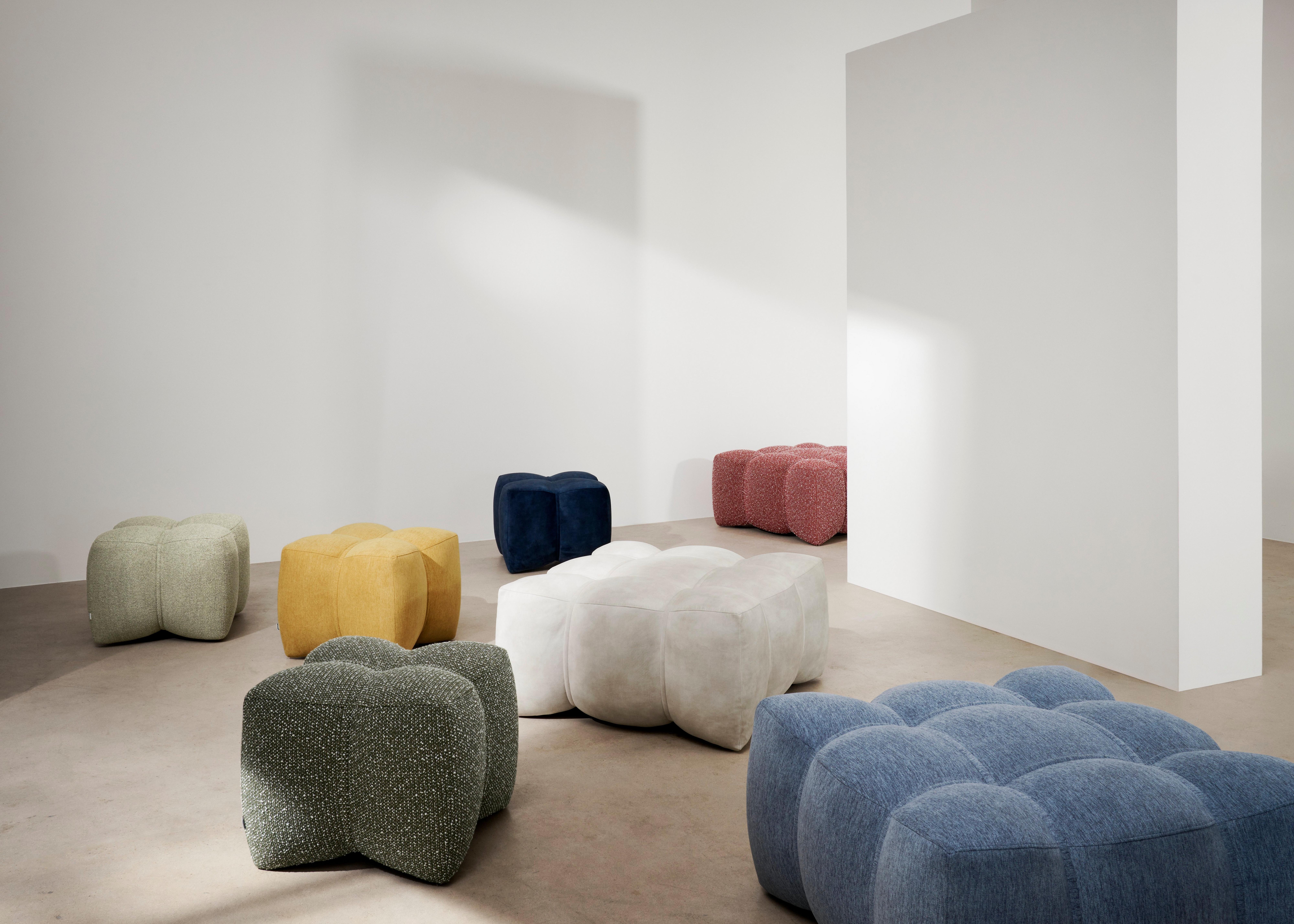 不同形狀和顏色的沙發凳，包括灰色、米色、黃色和白色，室內採用極簡風格。