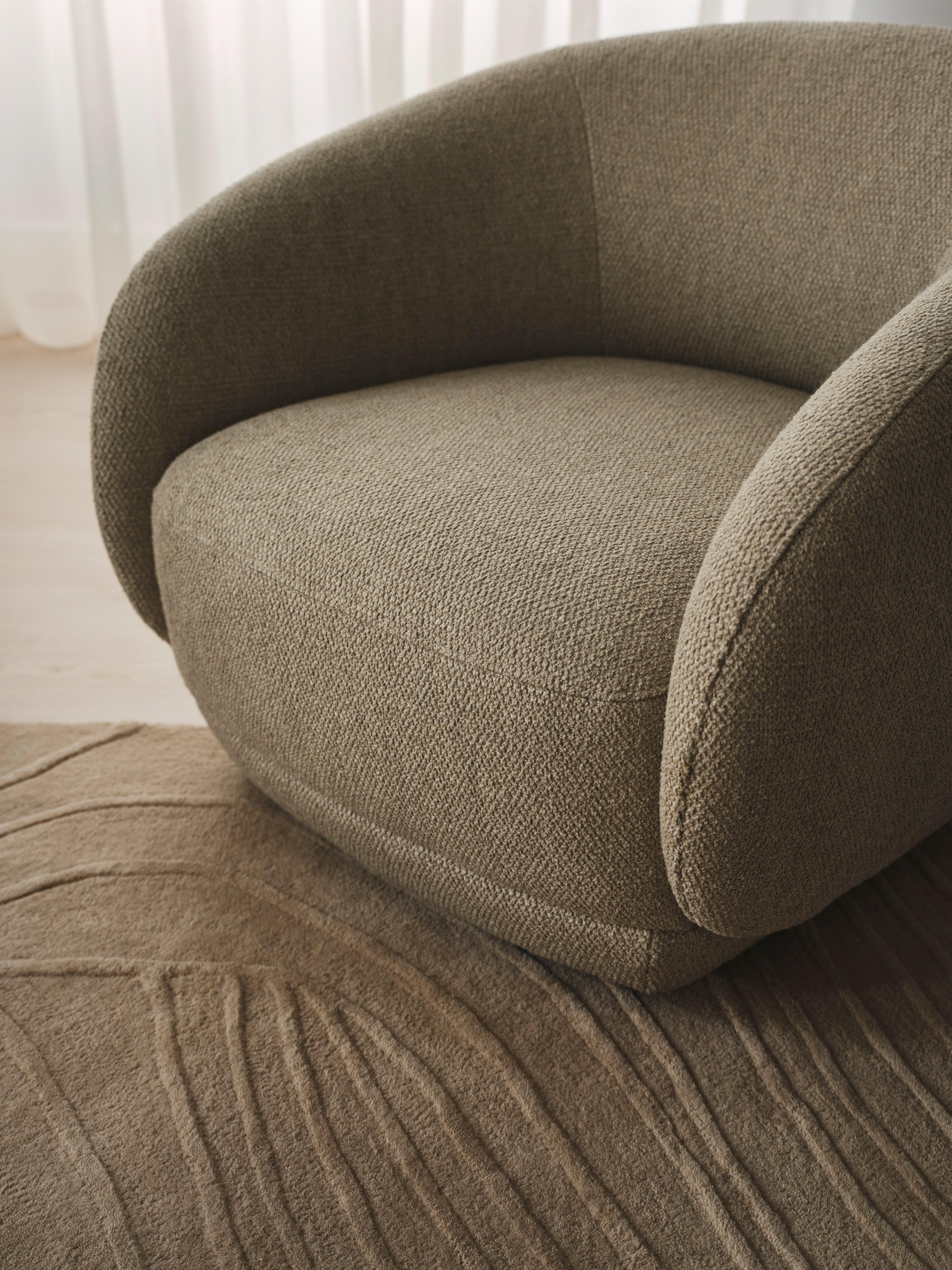 Poltrona cinzenta com tecido texturizado e tapete com padrão geométrico.