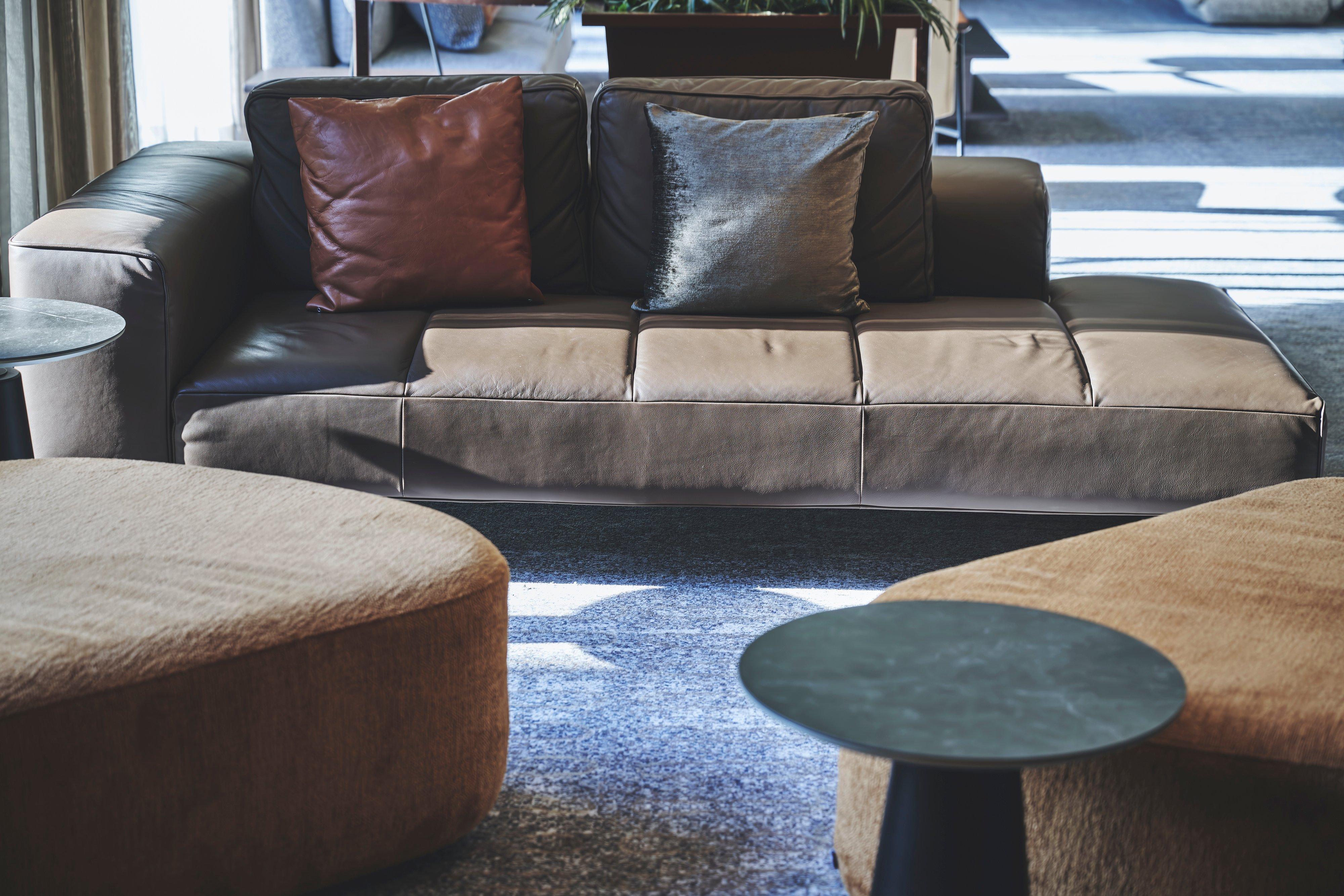 Dark leather sofa with two cushions in a living room setting.