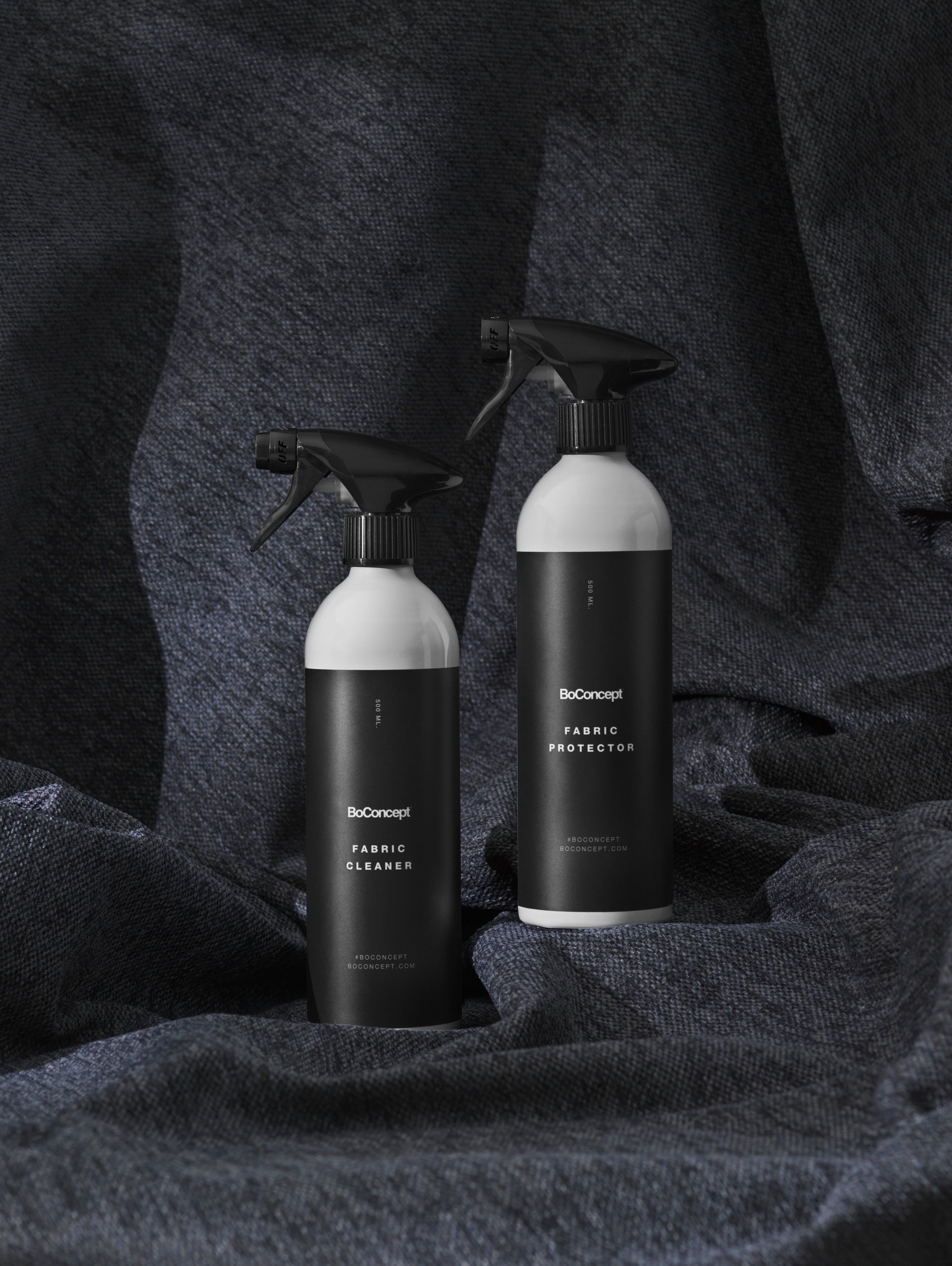 BoConcept fabric cleaner and protector bottles on a textured blue fabric.