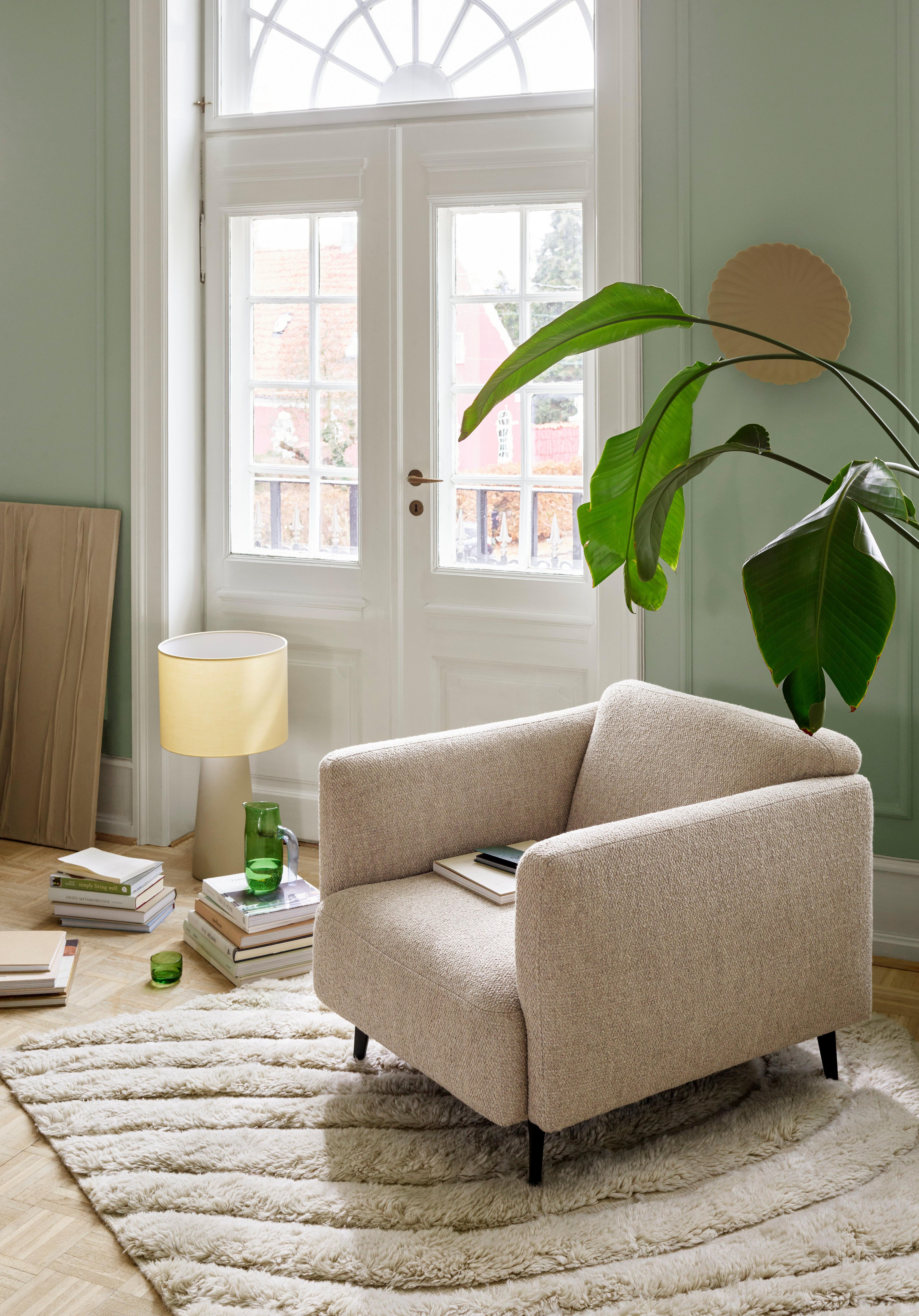 Modena armchair in beige fabric placed in light livingroom