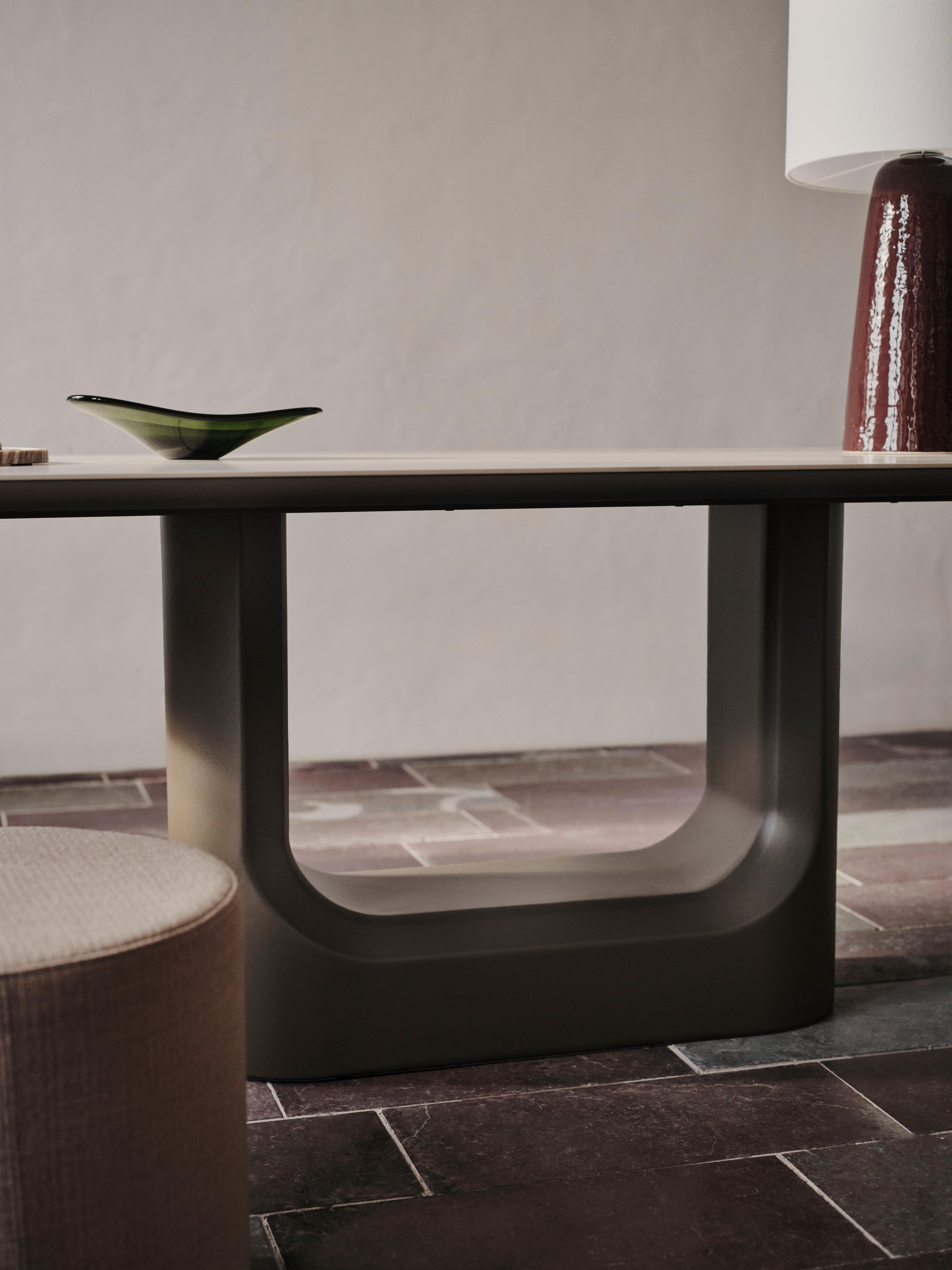Modern console table with U-shaped base, styled with a glass bowl and table lamp.
