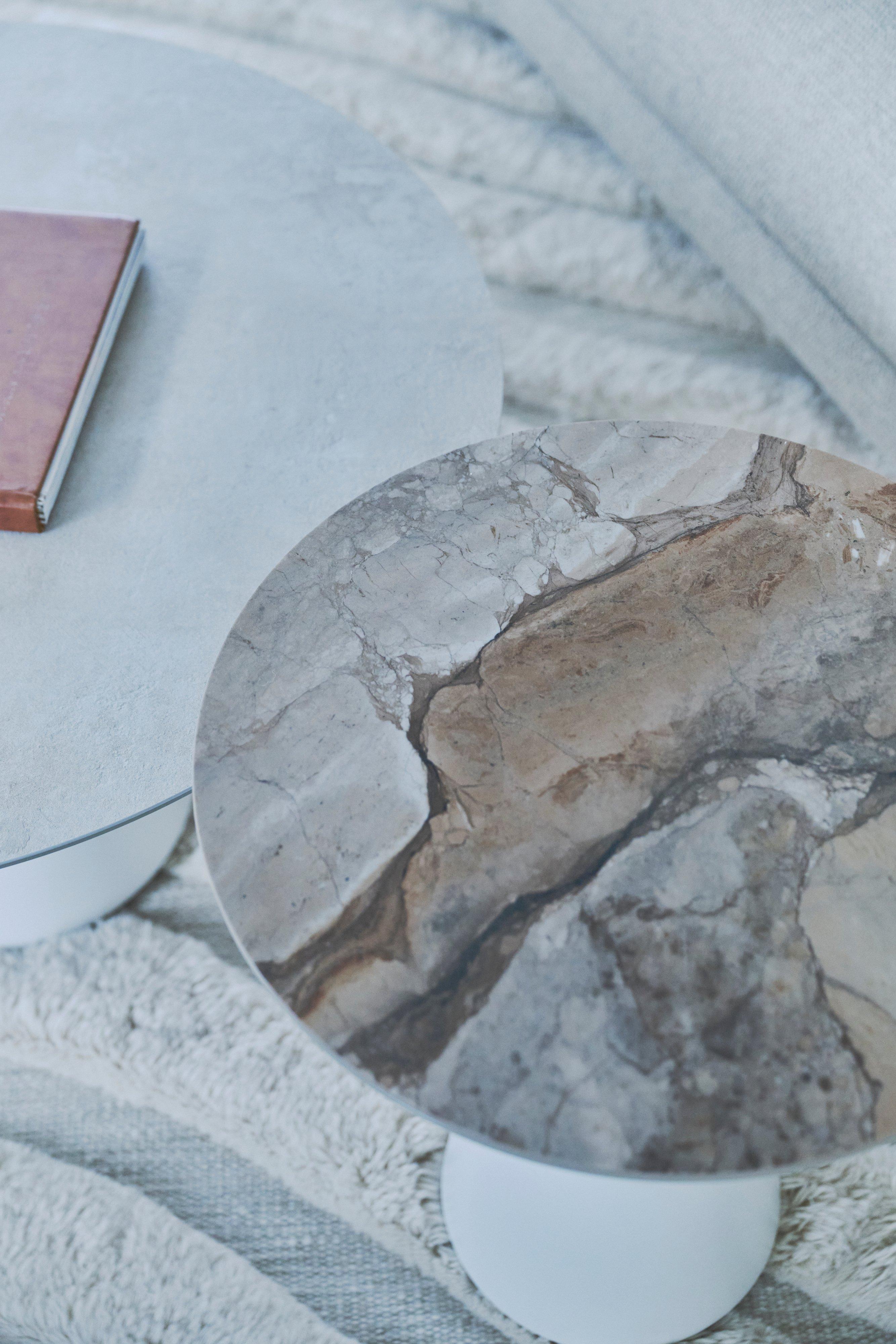 Two round nesting coffee tables with white bases and a grey marble-effect top.