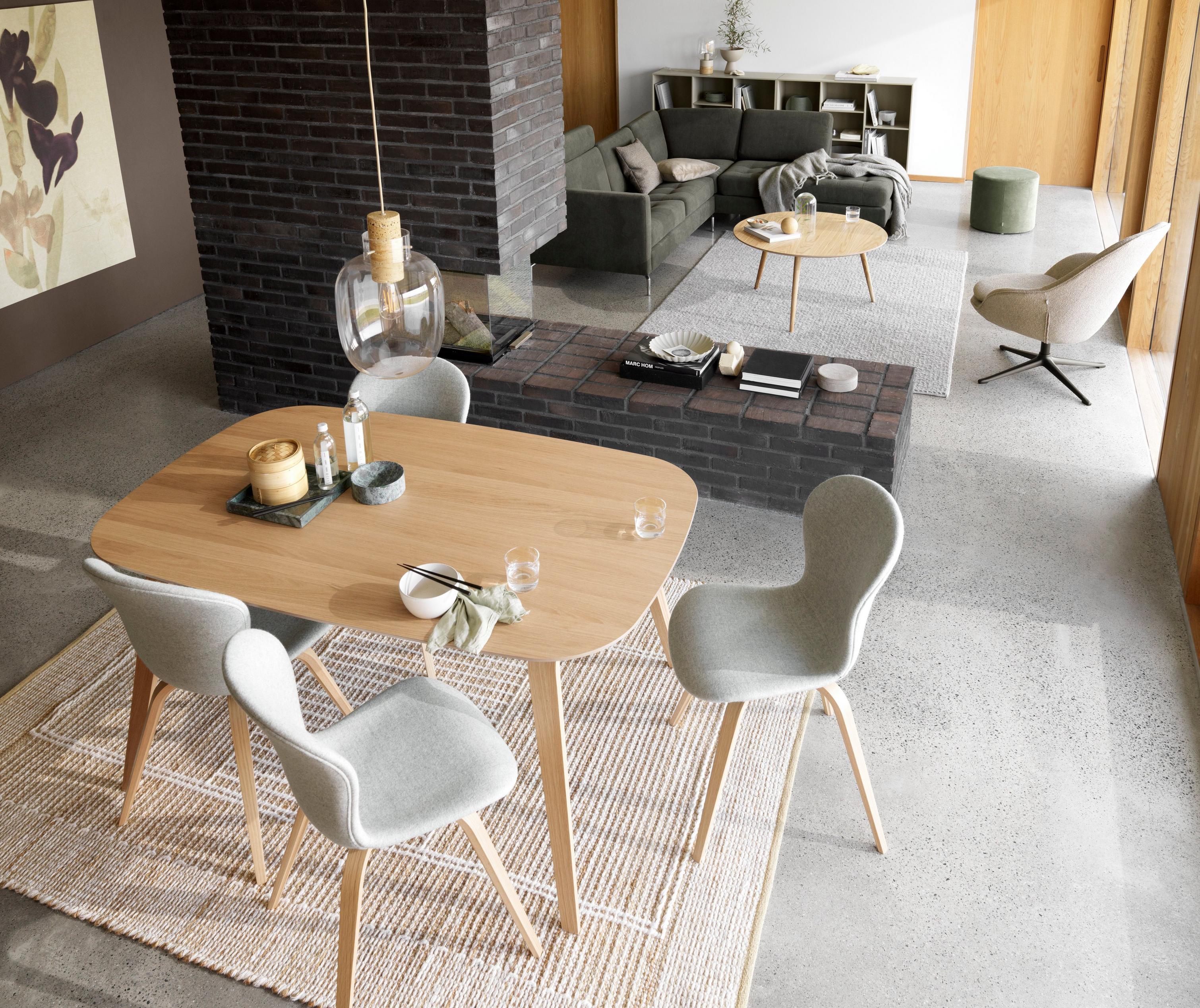 Stół i krzesła Hauge tapicerowane jasnoszarą, melanżową tkaniną Wellington, w tle sofa narożną Osaka w ciemnozielonej tkaninie Frisco.