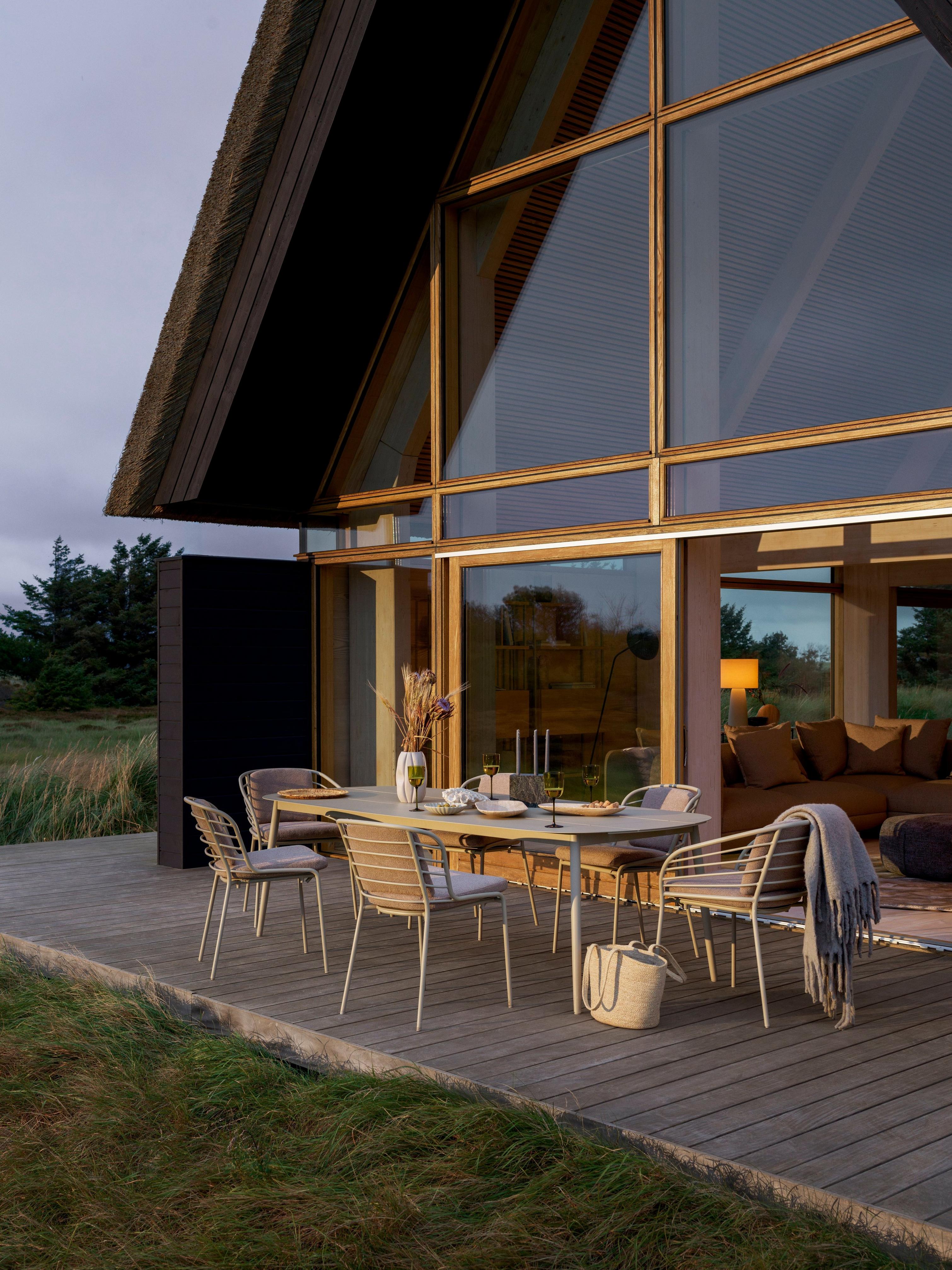 Open-air dining space at dusk featuring the Cancun dining table and dining chairs in matte ash gray.
