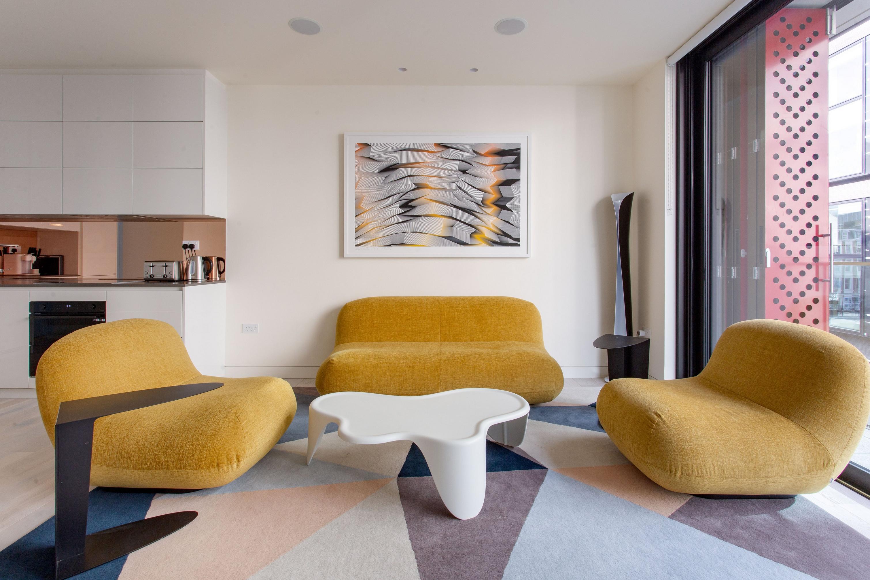 Modern living room with yellow Chelsea chairs, abstract art, and geometric rug.