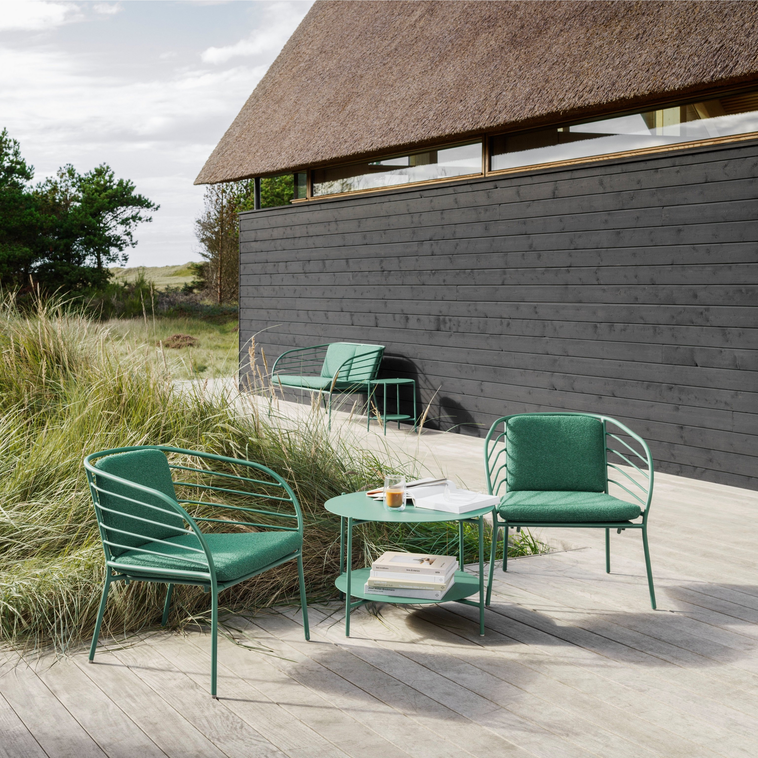 Stylish outdoor living space featuring the Cancún coffee table and lounge chairs in matt green.