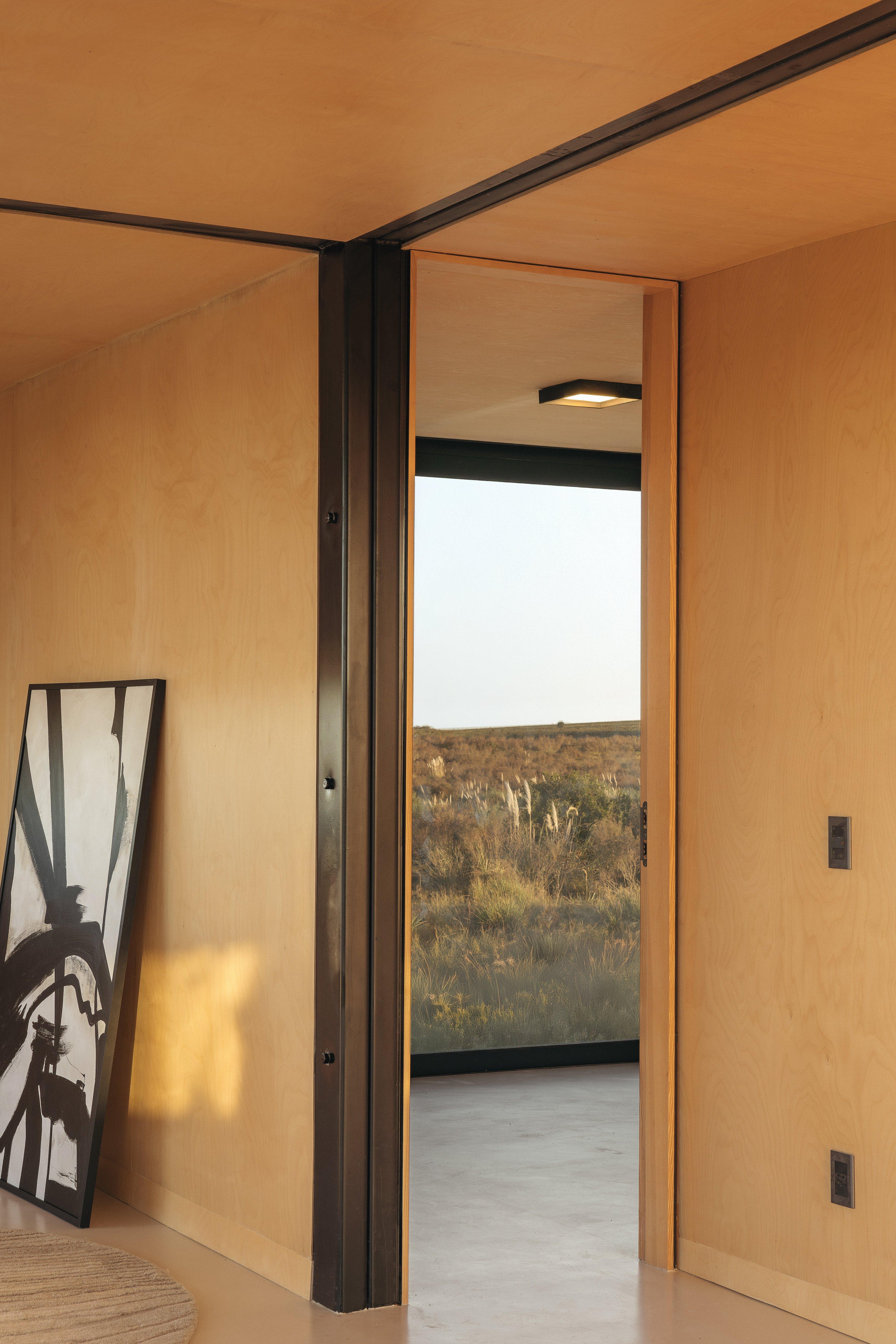 木質室內牆上掛著黑白畫，門外可見自然景觀。