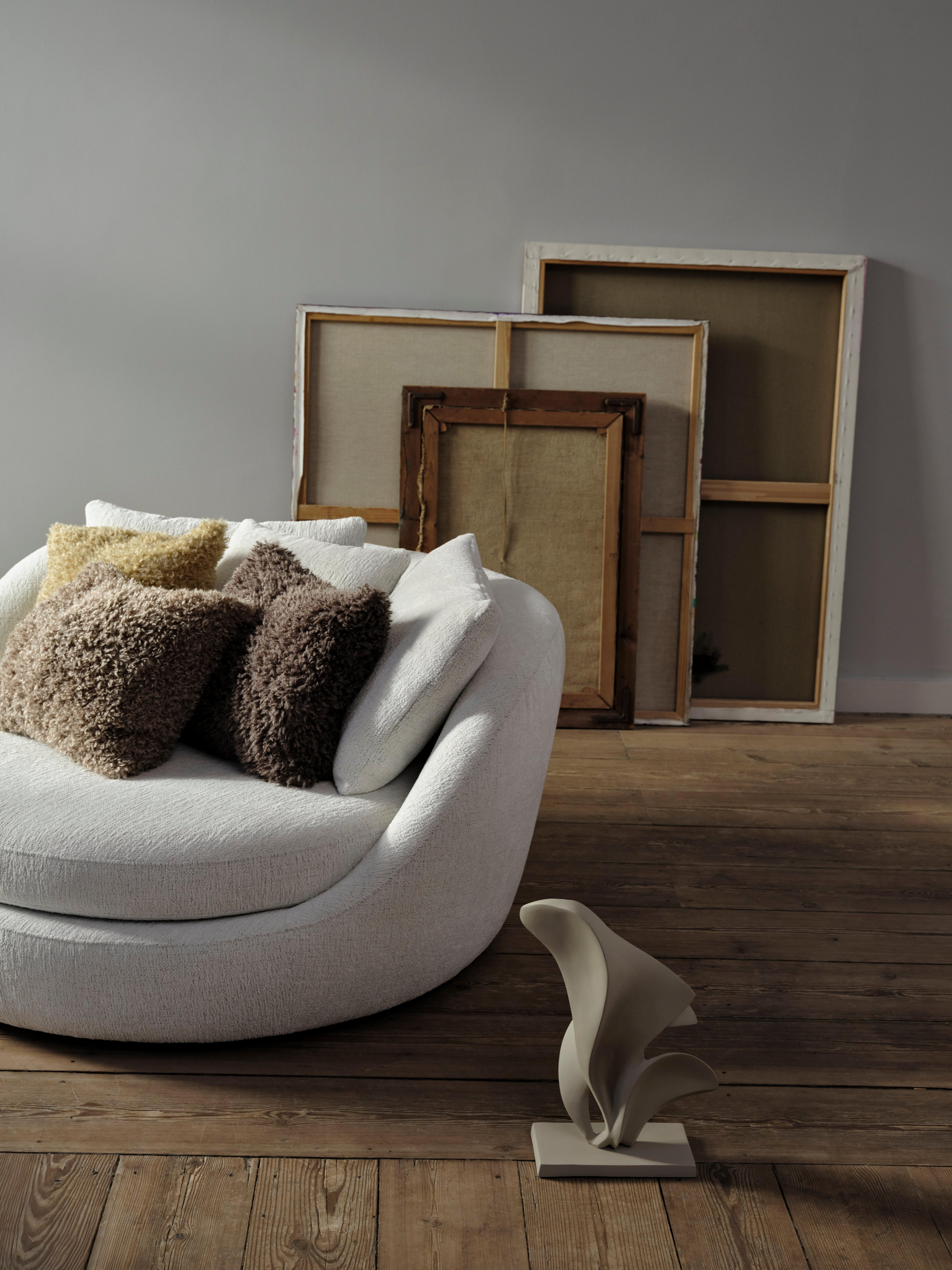 Colourful teddy and boucle cushions stacked on wooden floor with art in the background