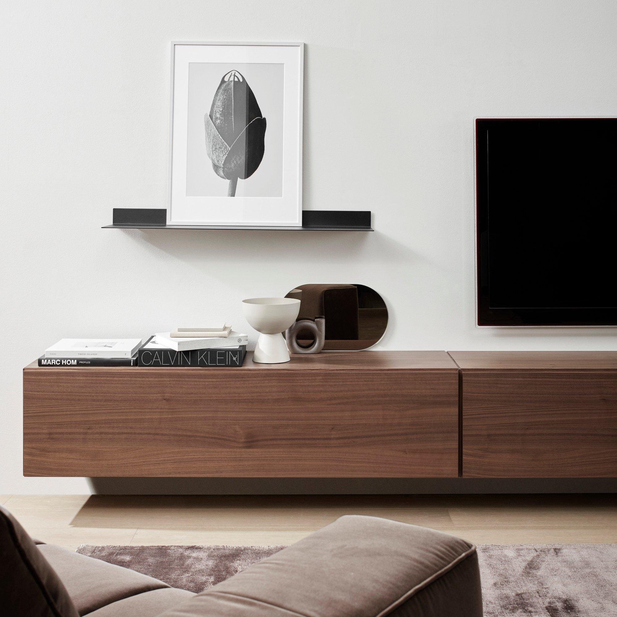 Detalle de sala minimalista con sofá marrón, módulo multimedia de madera, arte abstracto y decoración moderna.