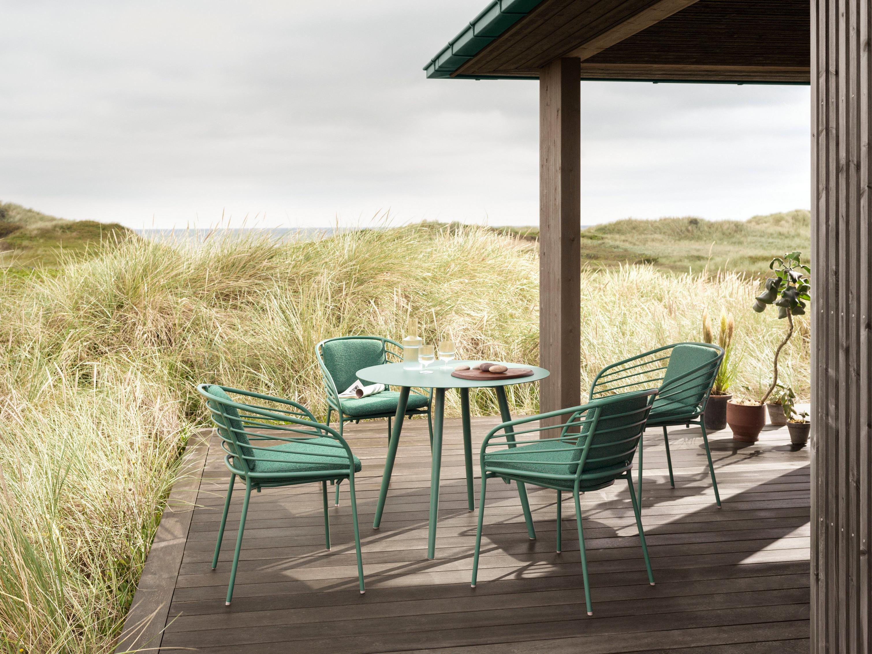 Elegant outdoor entertainment area featuring the Cancún Café table and dining chairs in matt green.