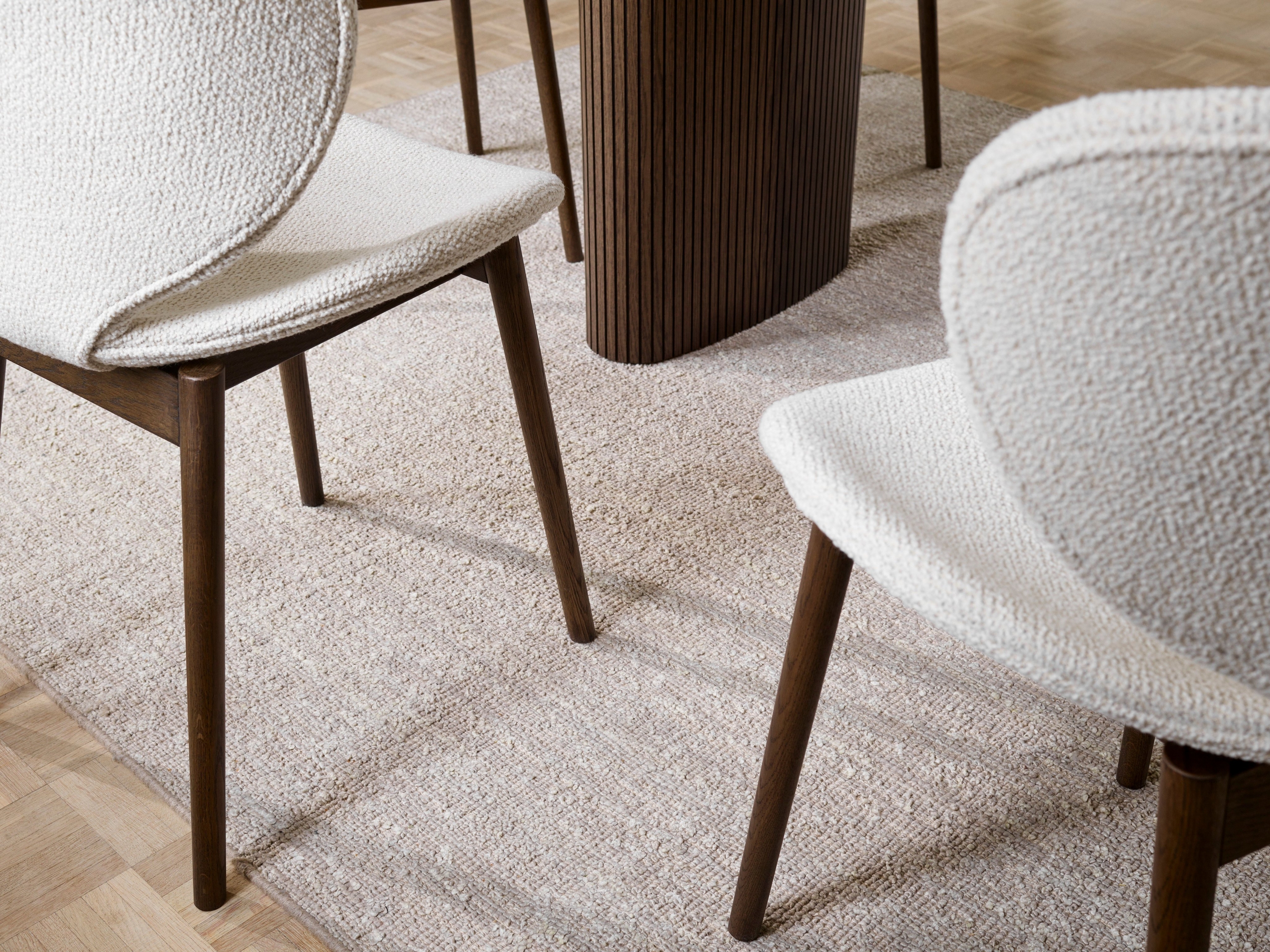 Textúrované stoličky Hamilton a koberec s dreveným stolom, zaostrené na detaily podlahy.
