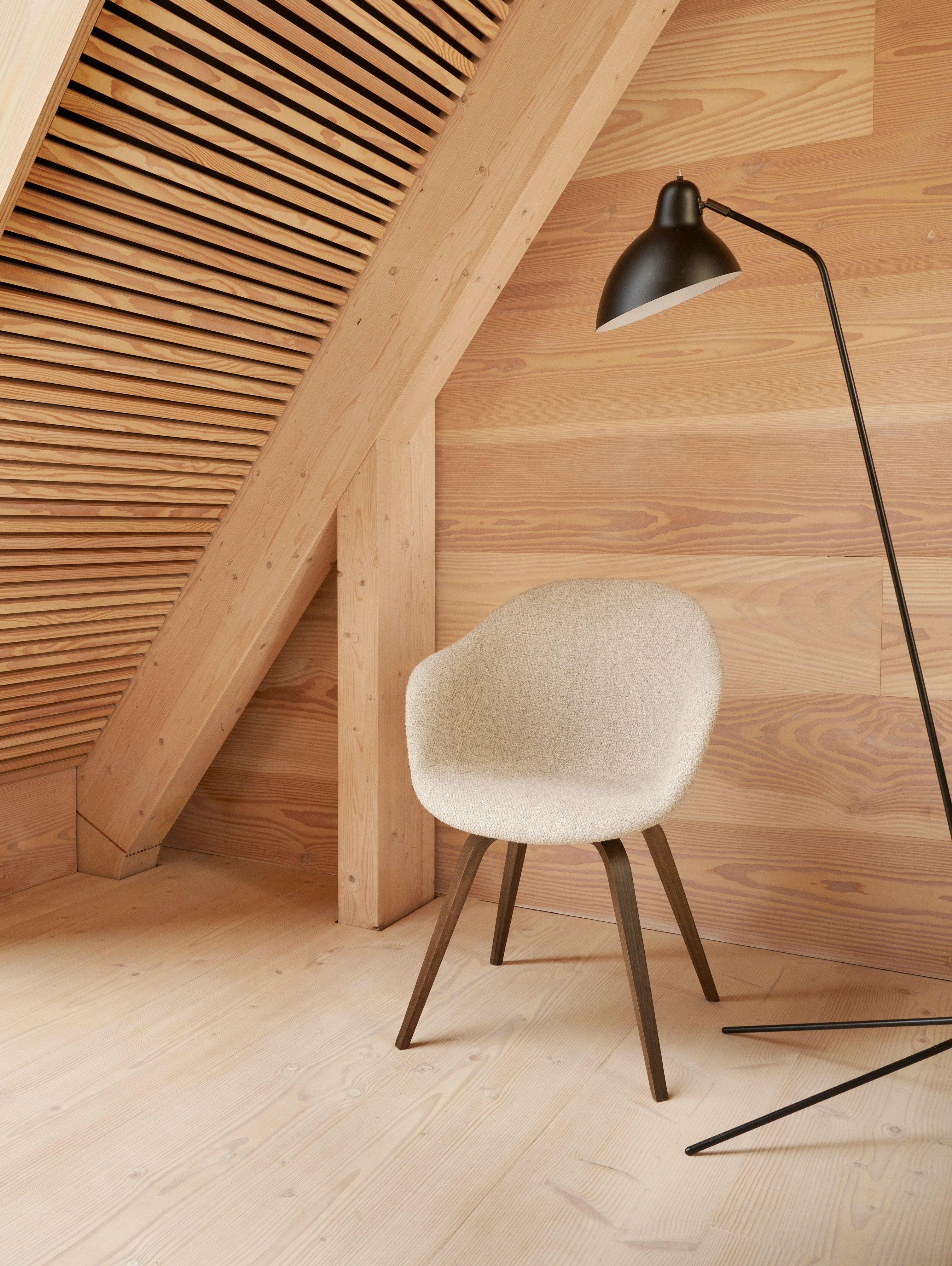 角落中的 Hauge 餐椅採用米色 Lazio 布料襯墊，搭配 Demand 落地燈。